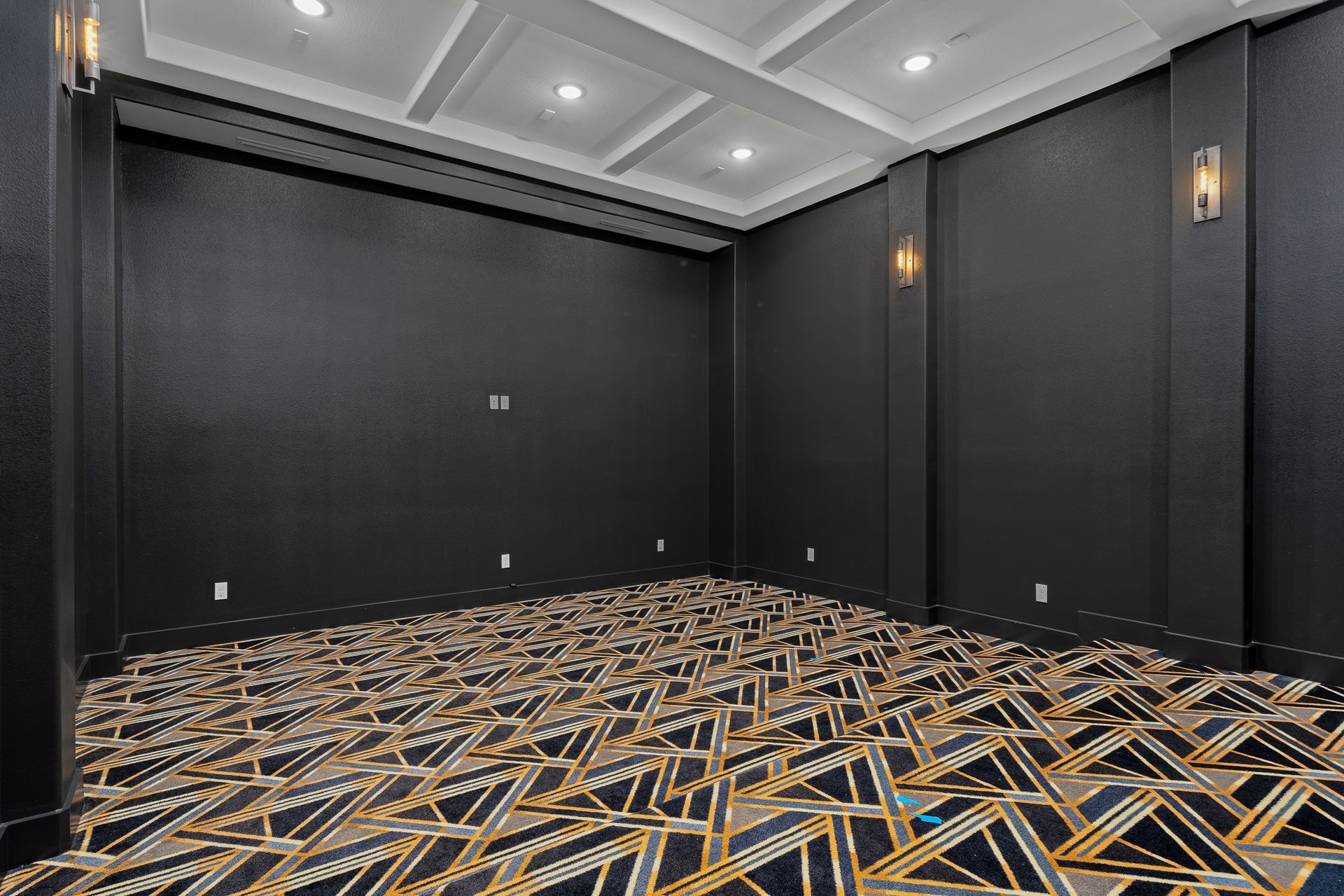 An empty room with a patterned carpet and black walls.