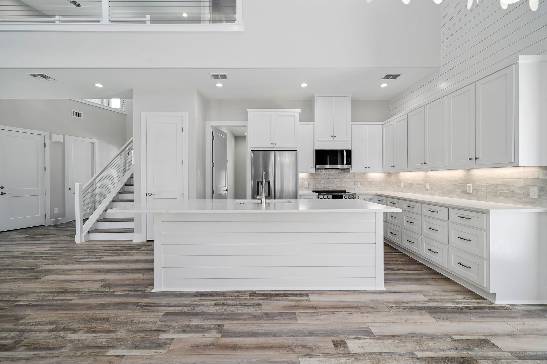 A kitchen with white cabinets , stainless steel appliances , and a large island.