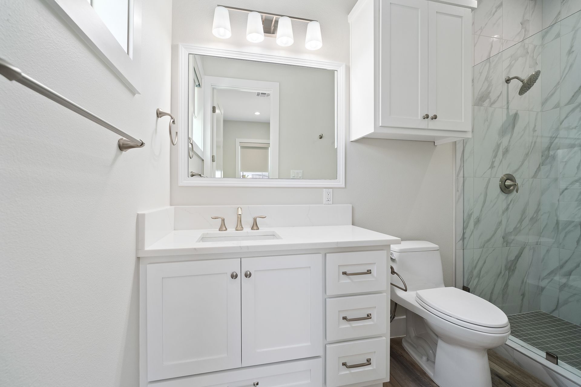 A bathroom with a sink , toilet , mirror and shower.