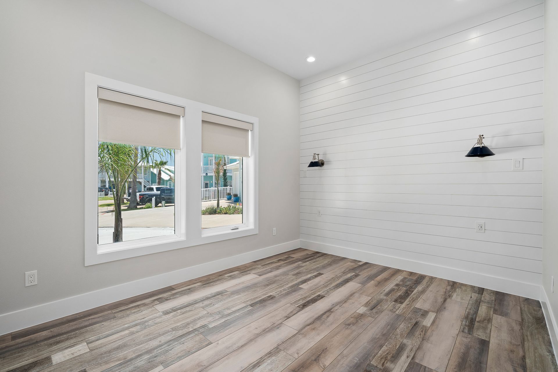 An empty room with a wooden floor and two windows.