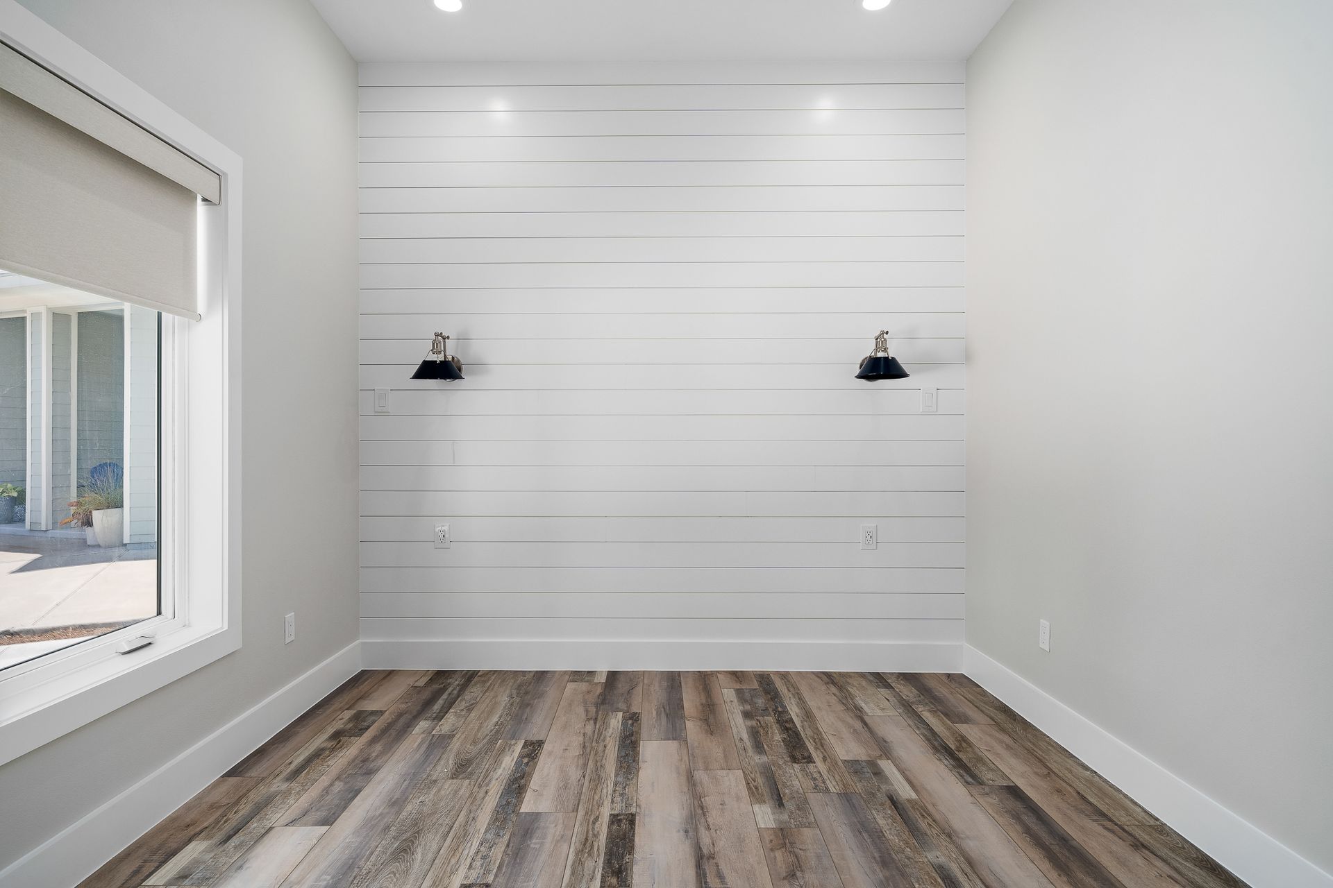 An empty room with hardwood floors , white walls and a window.