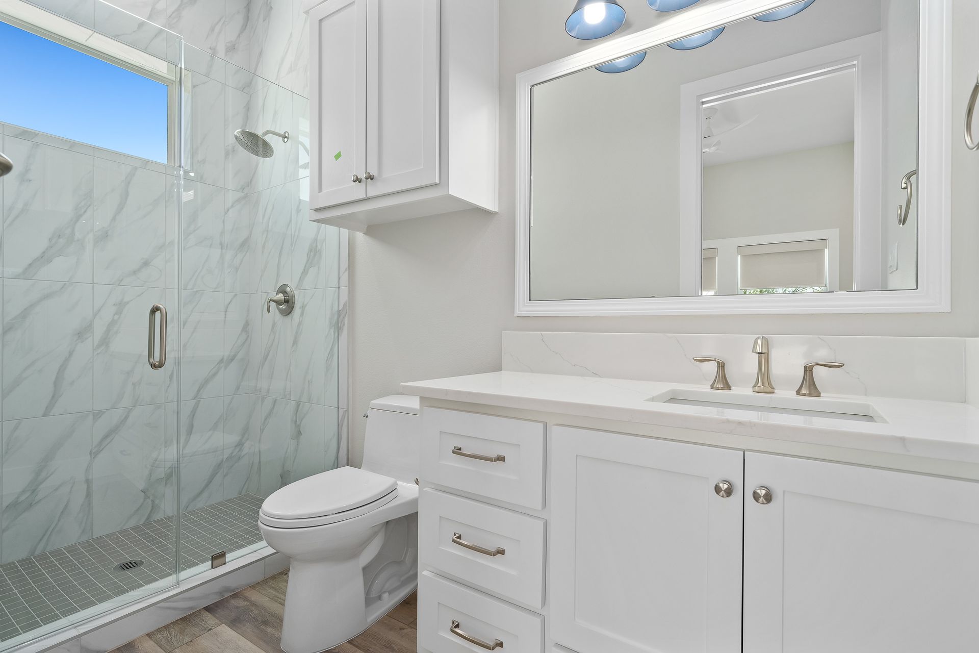 A bathroom with a toilet , sink , mirror and walk in shower.