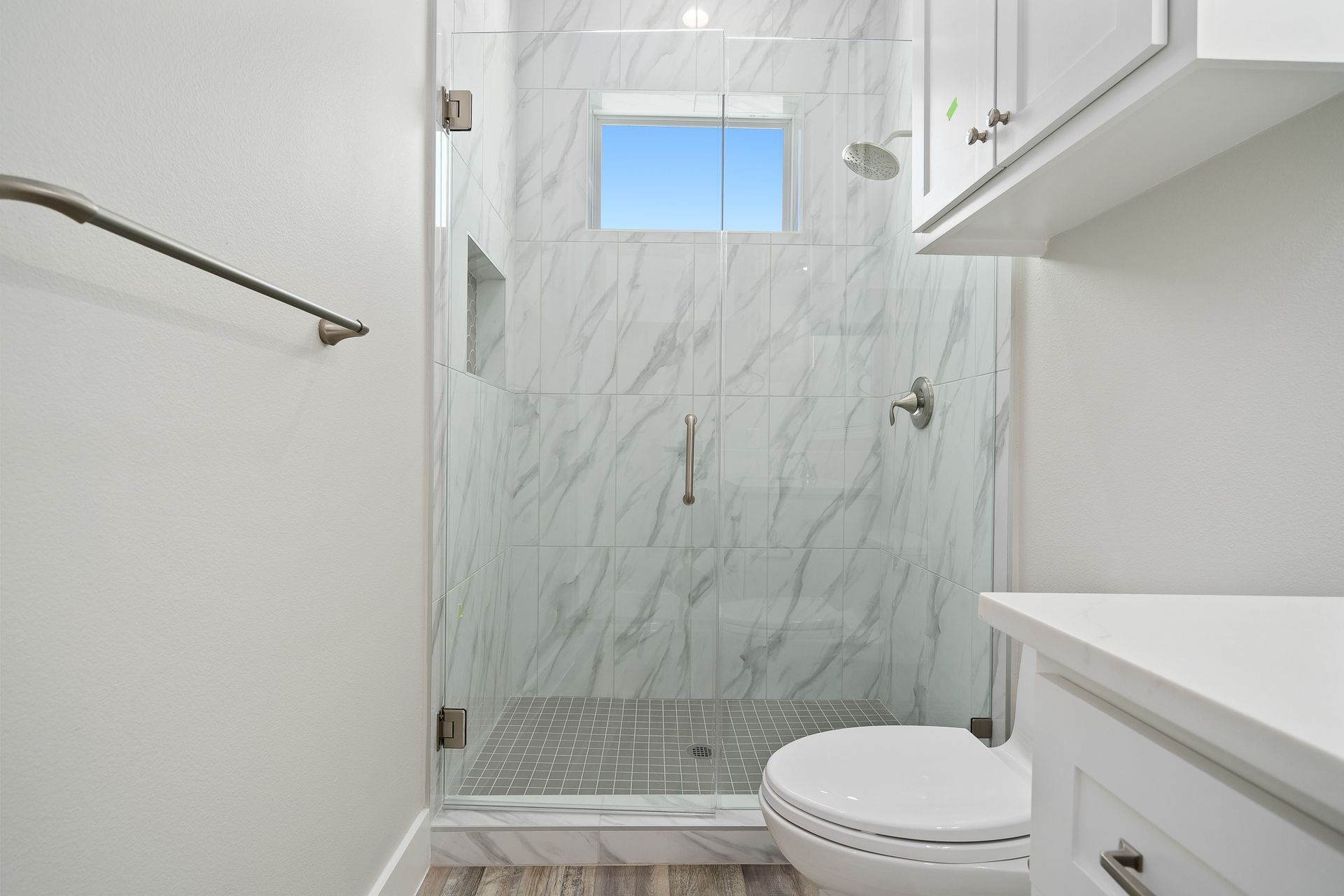 A bathroom with a toilet , sink , shower and window.