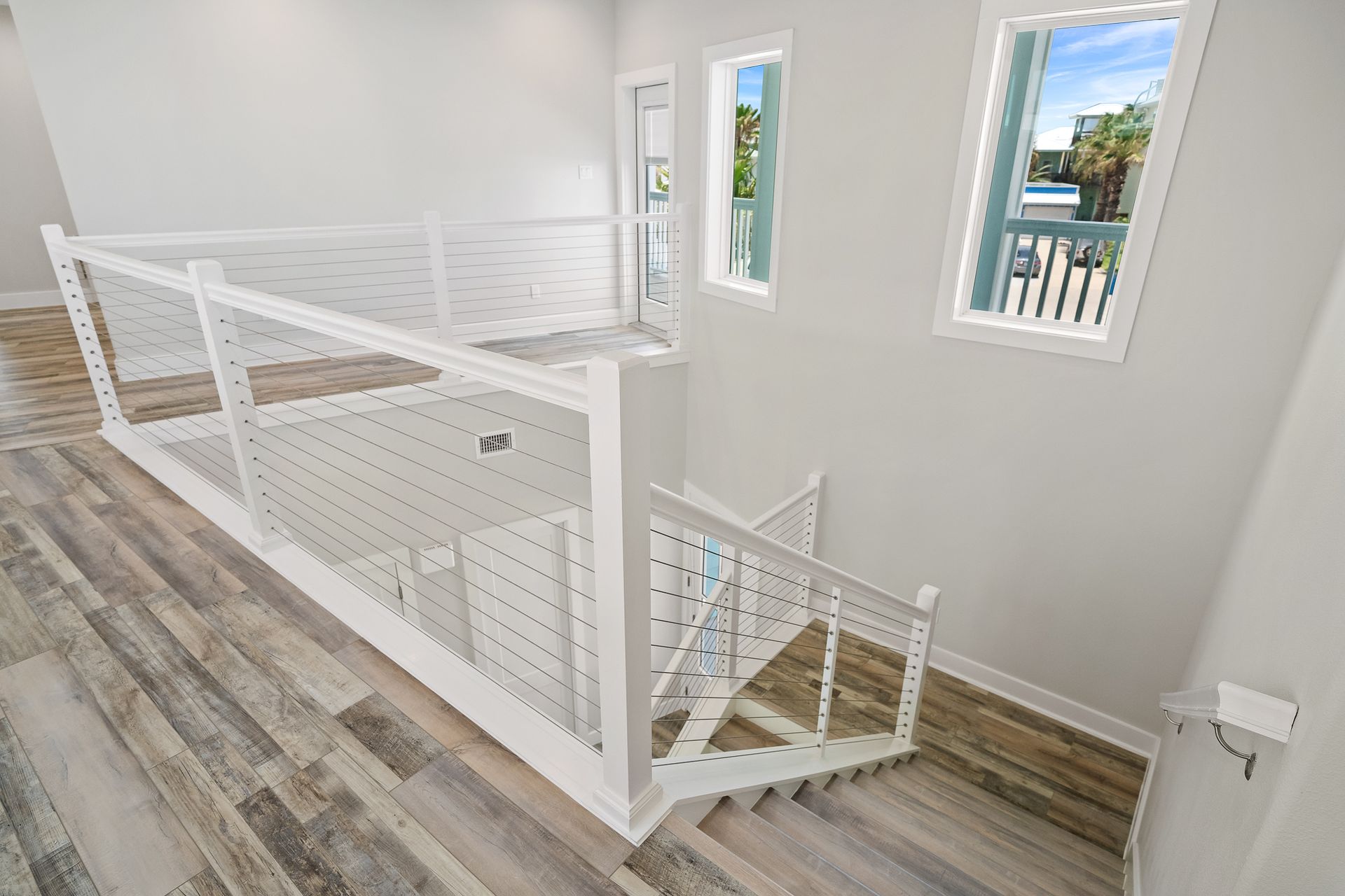 A white staircase with a wooden floor and a balcony in a house.