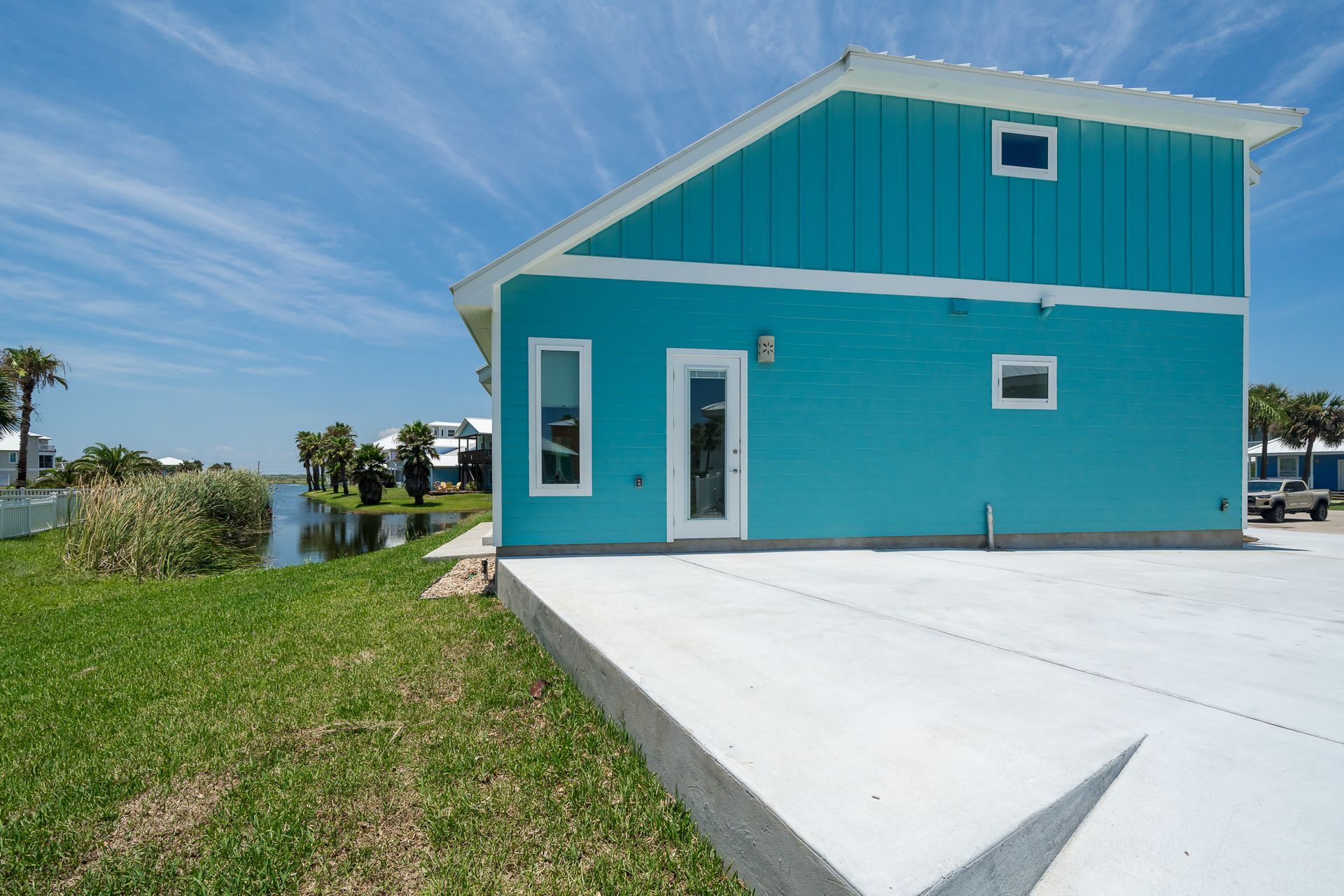 A blue and white house with a concrete driveway in front of it
