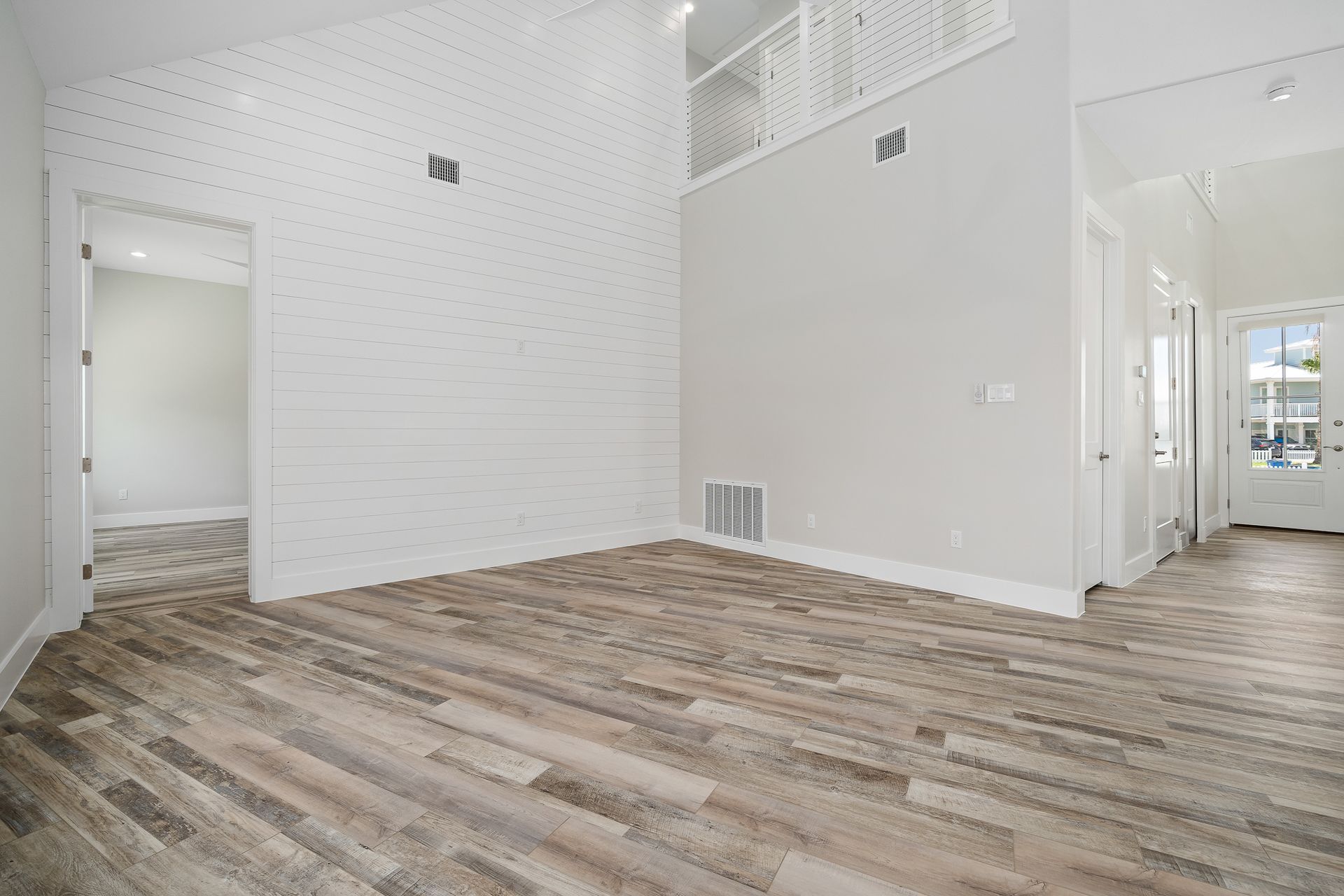 An empty living room with hardwood floors and white walls.