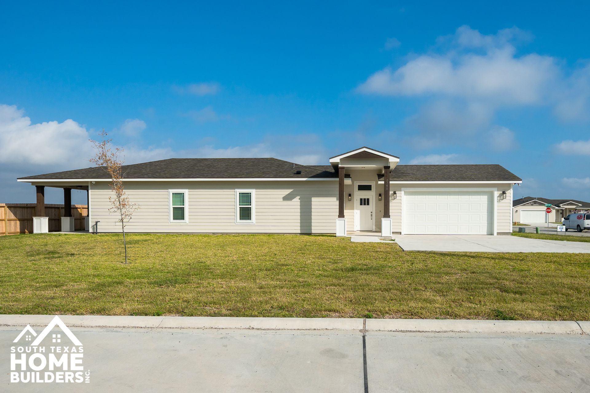 A large white house with a black roof is sitting in the middle of a field.