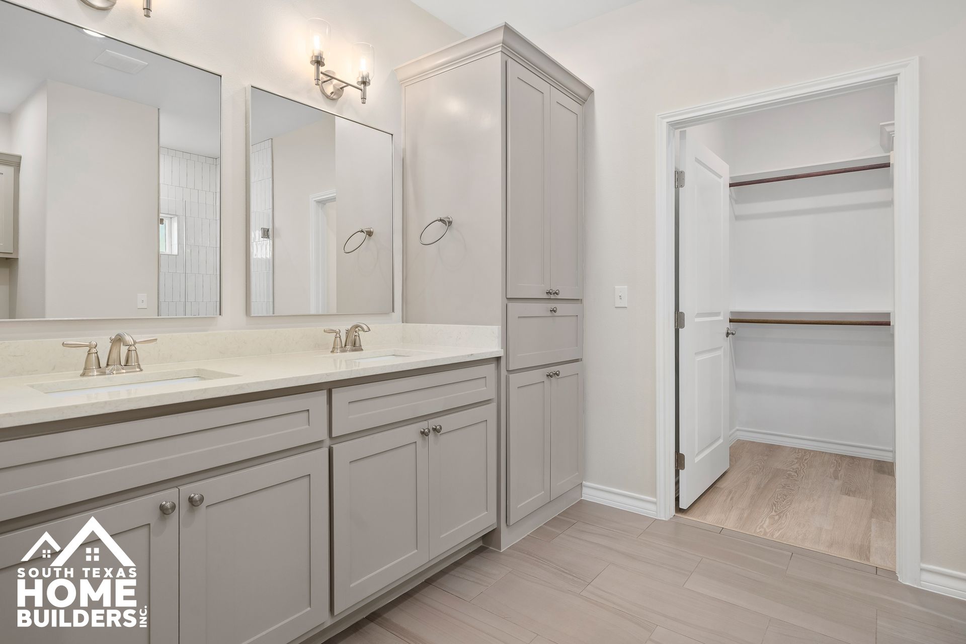 Bathroom with gray cabinets, white countertops, two mirrors, and a walk-in closet.