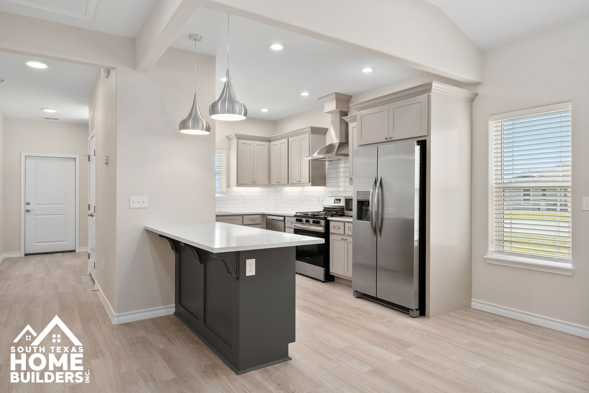 Open-concept kitchen with gray cabinets, stainless steel appliances, and a breakfast bar.