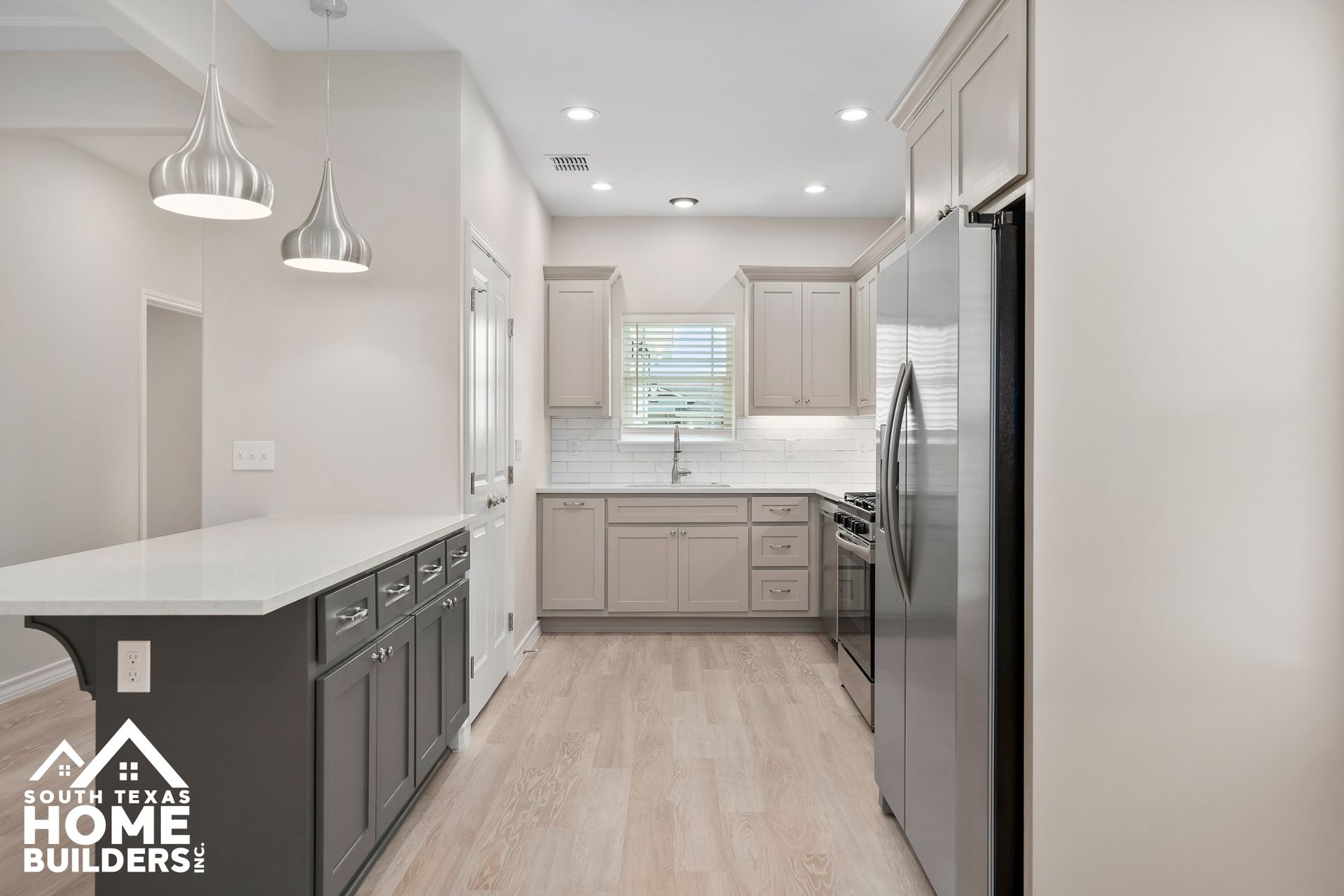 Modern kitchen with gray cabinets, white countertops, and stainless steel appliances.