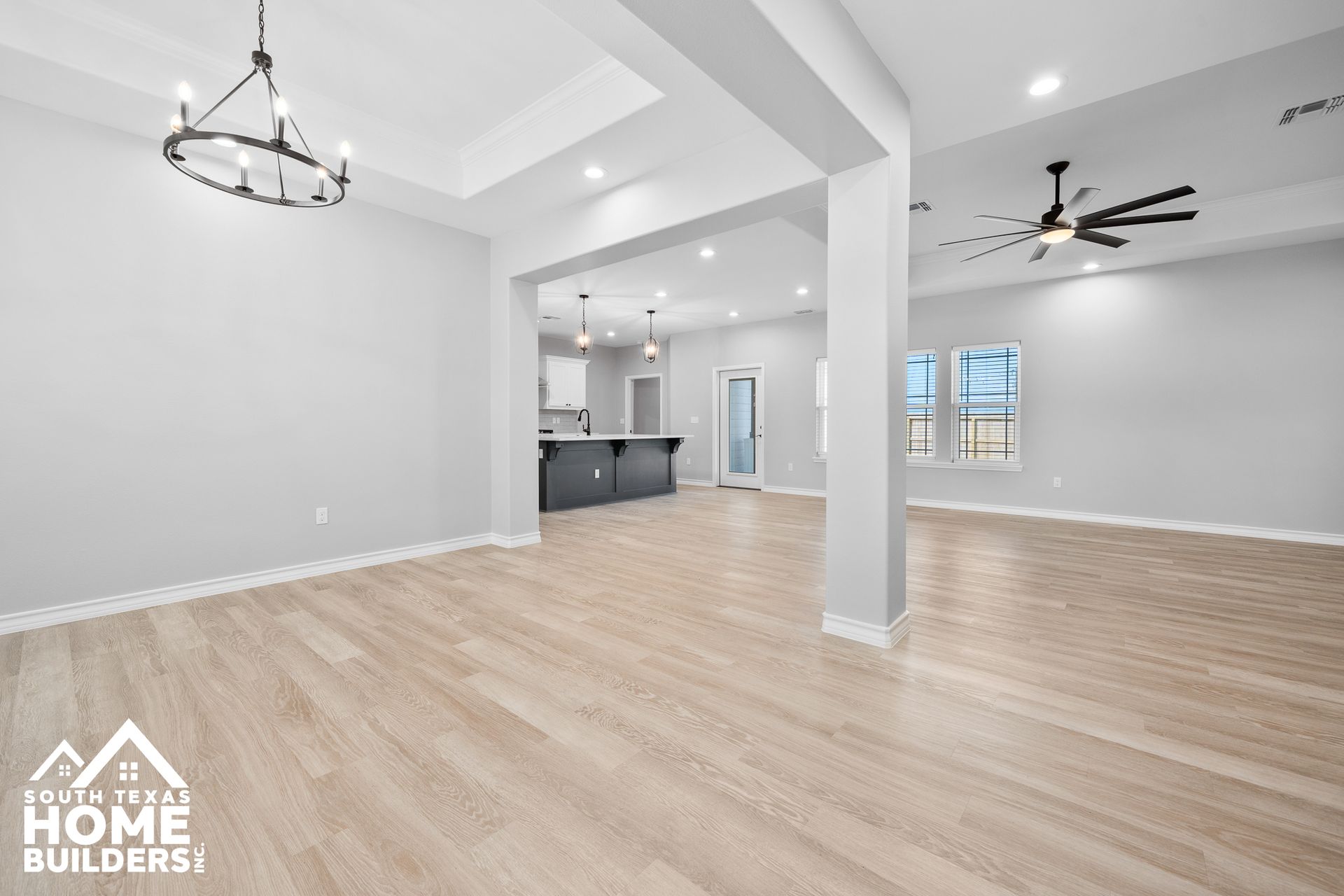 Empty, light-filled living area with hardwood floors, gray walls, and open layout.