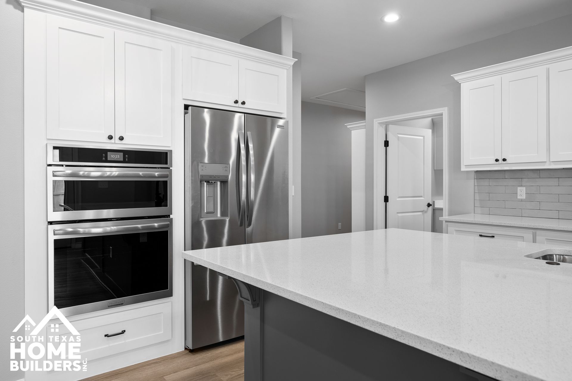 Modern kitchen with white cabinets, stainless steel appliances, and gray island.
