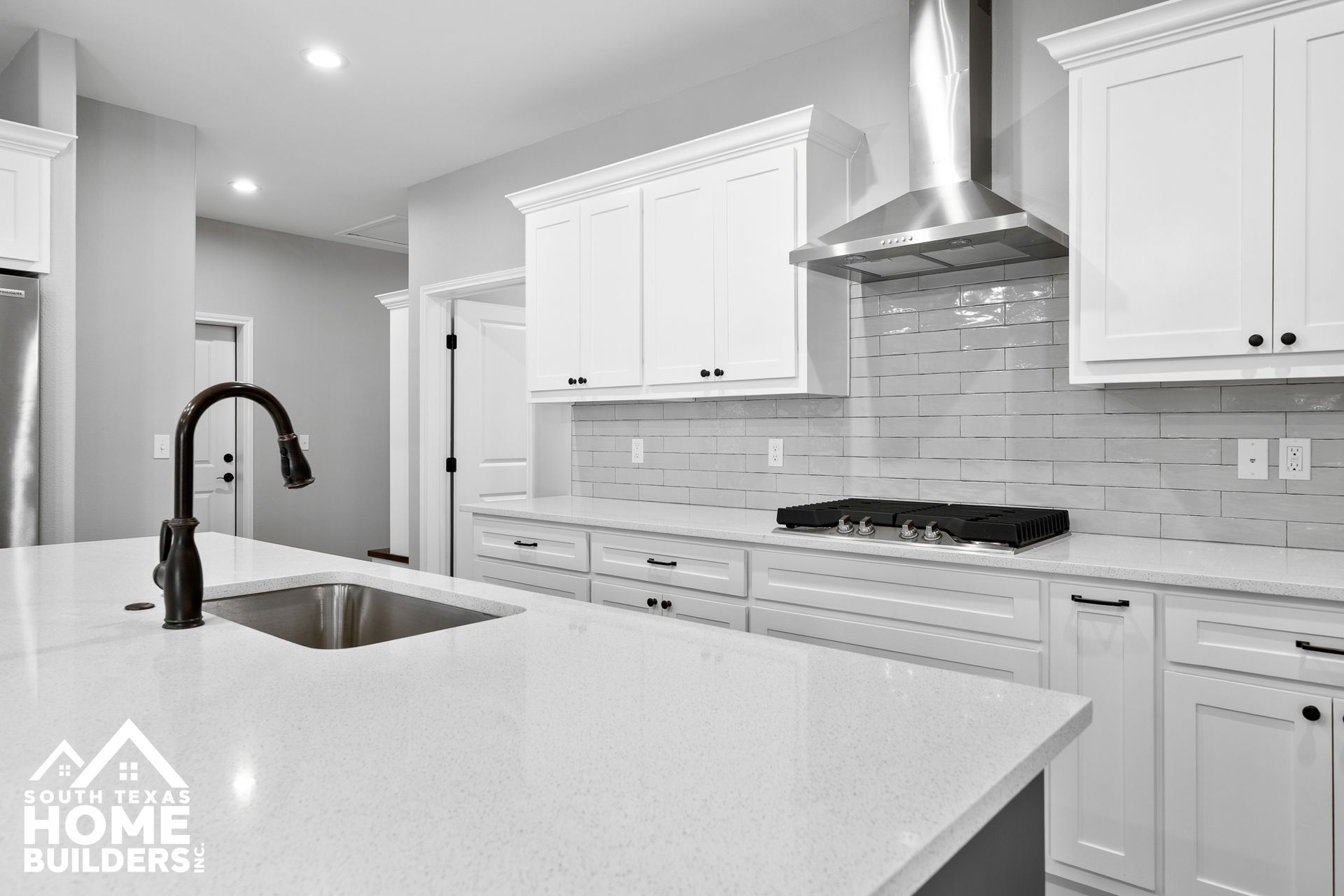 Modern kitchen with white cabinets, island with sink, and stainless steel range hood.