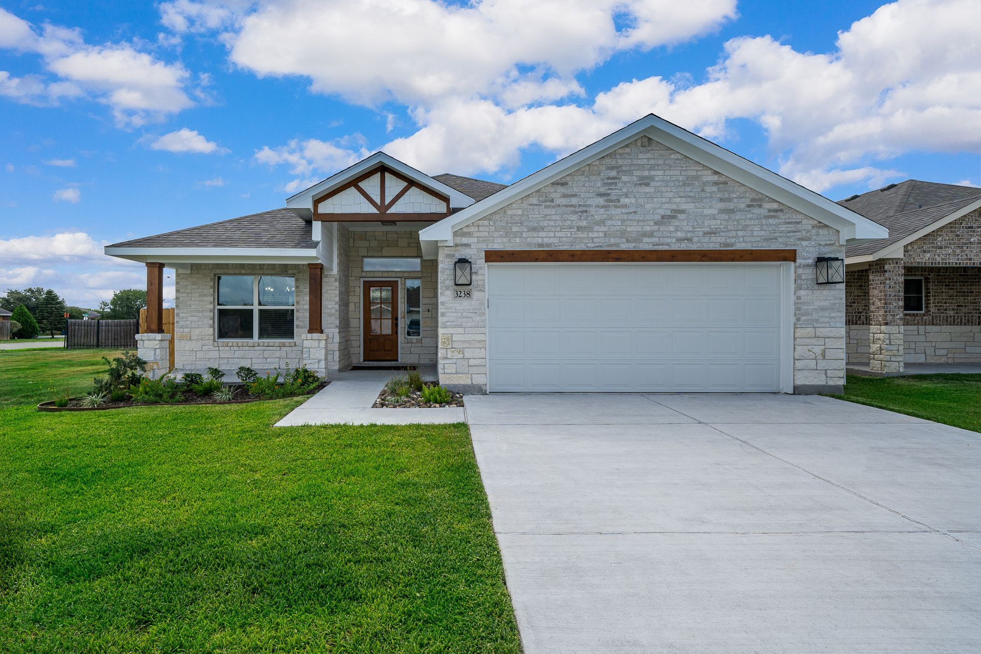 A house with a white garage door is sitting on top of a lush green field.