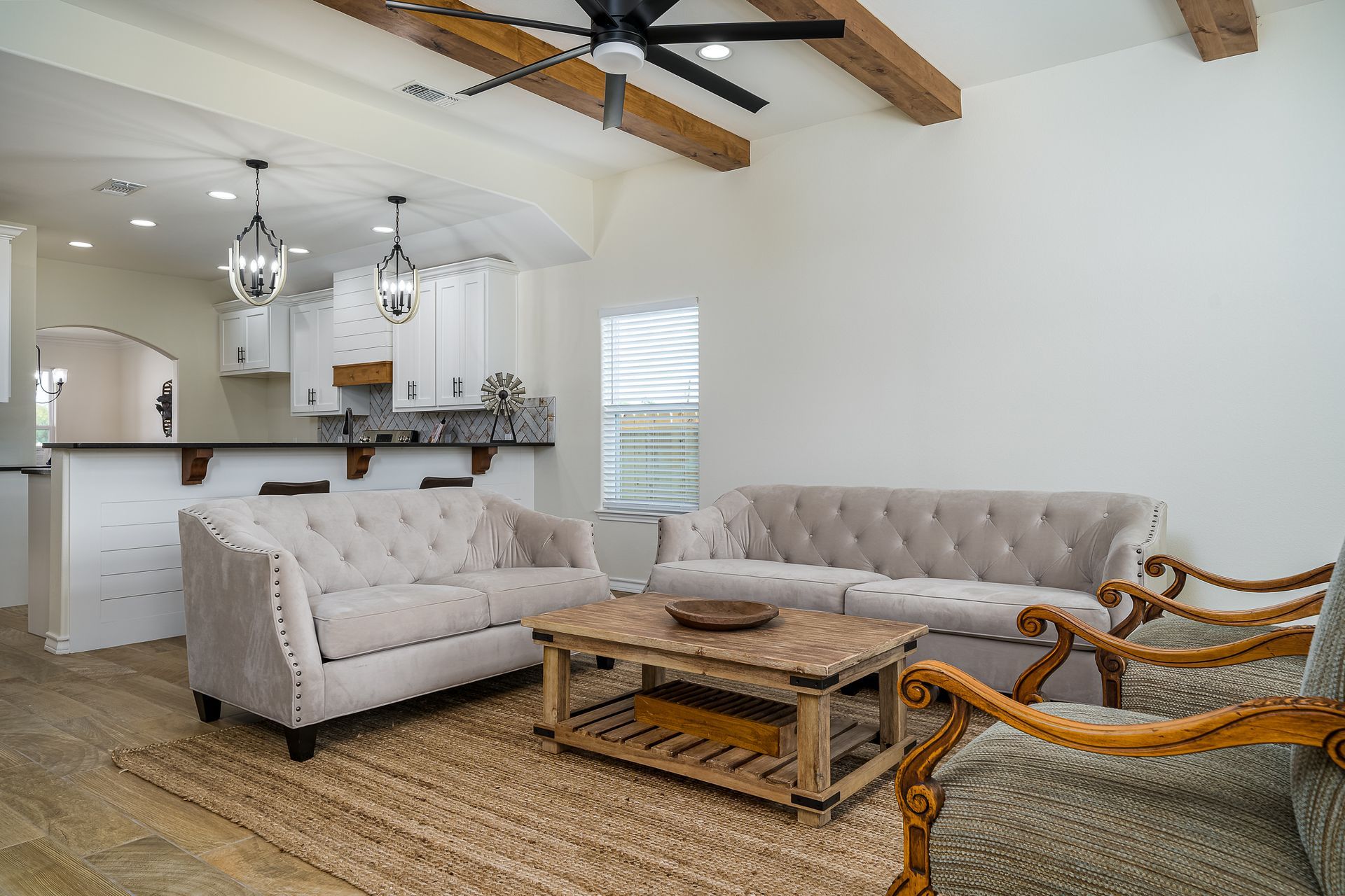 A living room with a couch , chair , coffee table and ceiling fan.