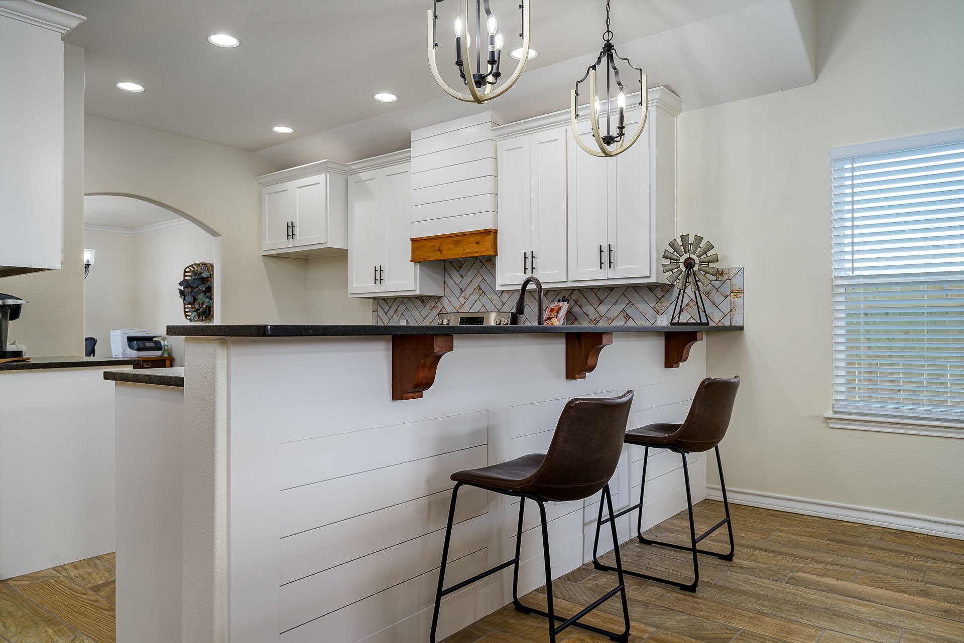 A kitchen with white cabinets and a bar with two chairs