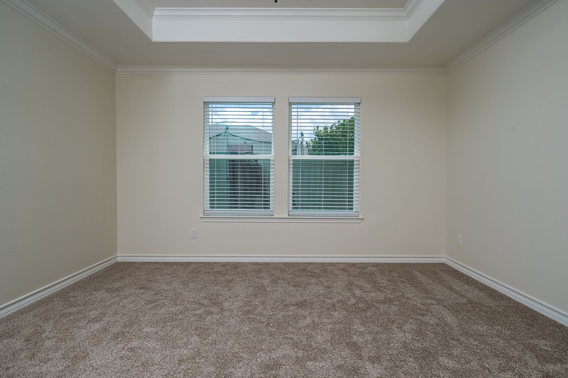 An empty room with two windows and a carpeted floor.