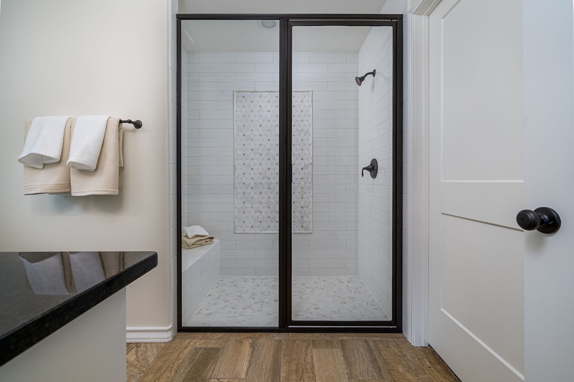 A bathroom with a walk in shower and two towels hanging on the wall.