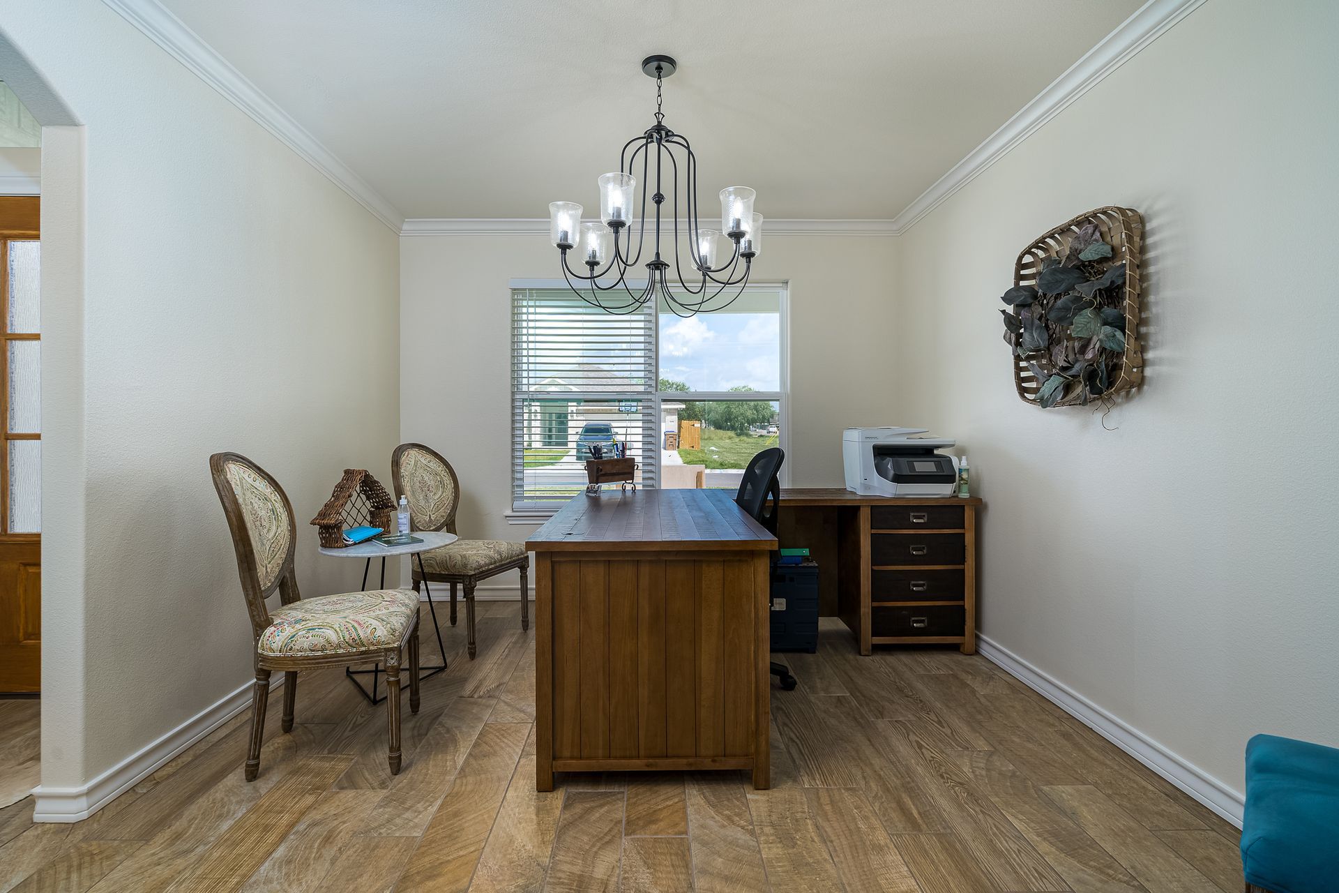A room with a desk , chairs , and a chandelier.