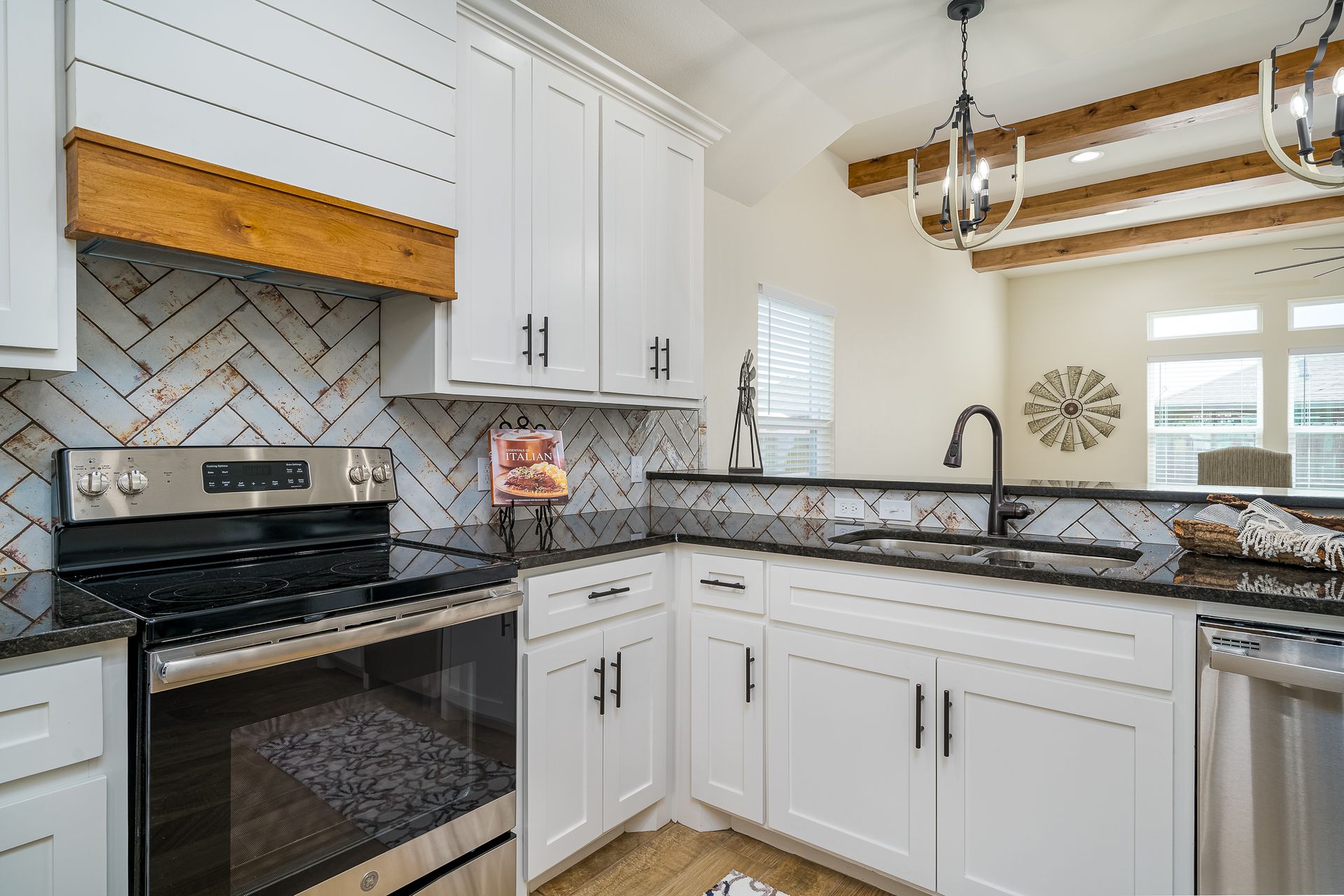 A kitchen with white cabinets , stainless steel appliances , a stove and a sink.