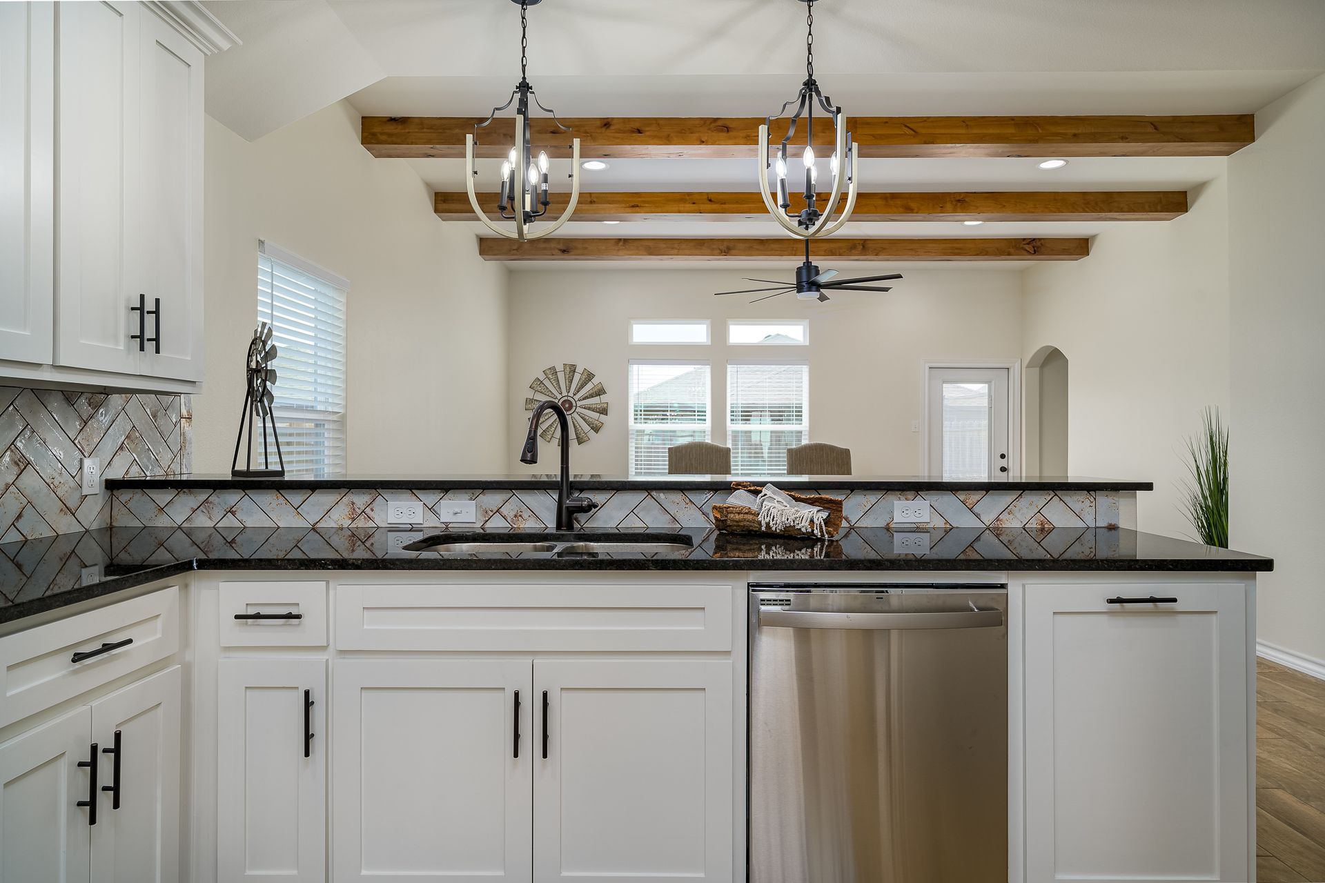 A kitchen with white cabinets , black counter tops , and stainless steel appliances.