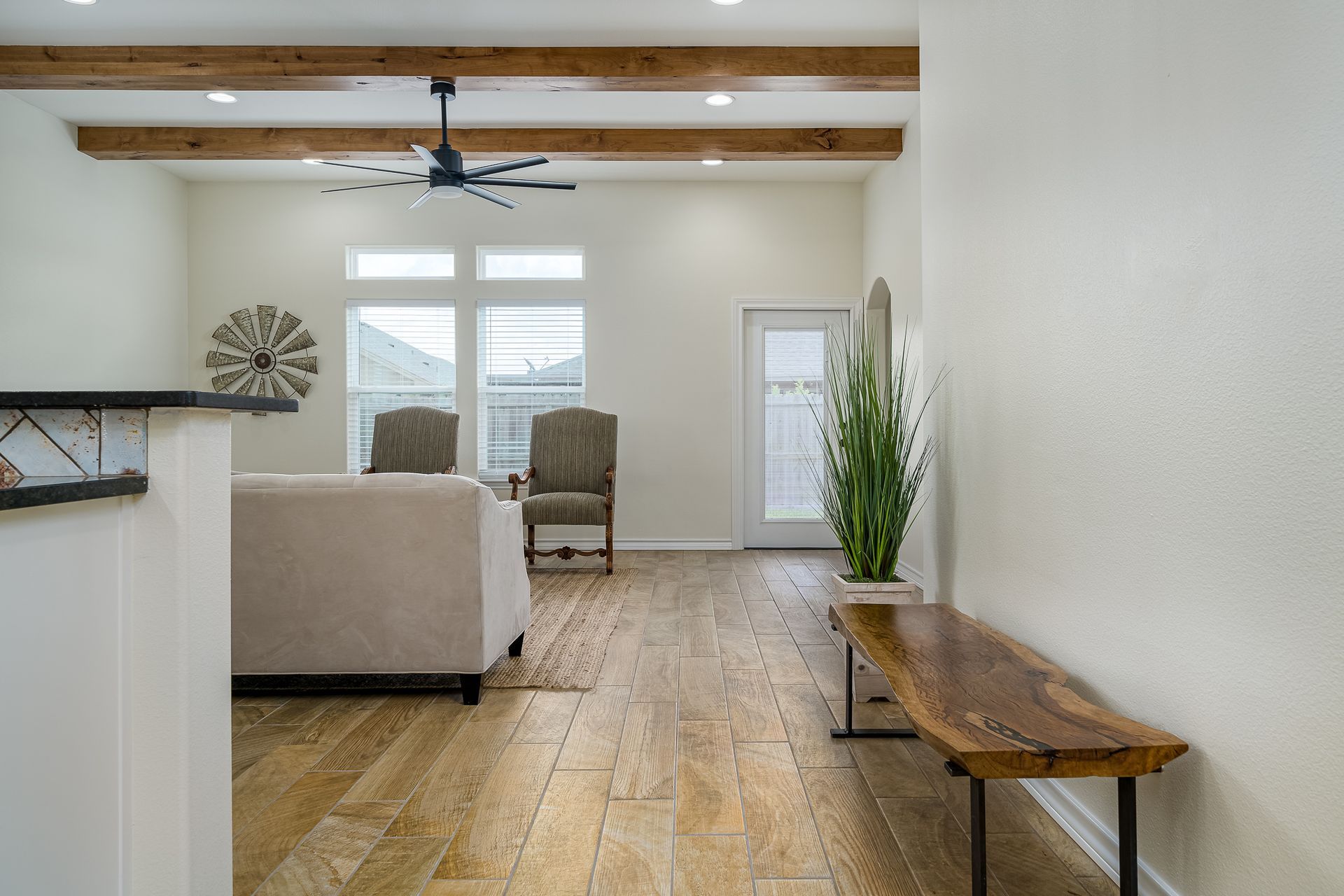 A living room with a couch , chairs , a table and a ceiling fan.
