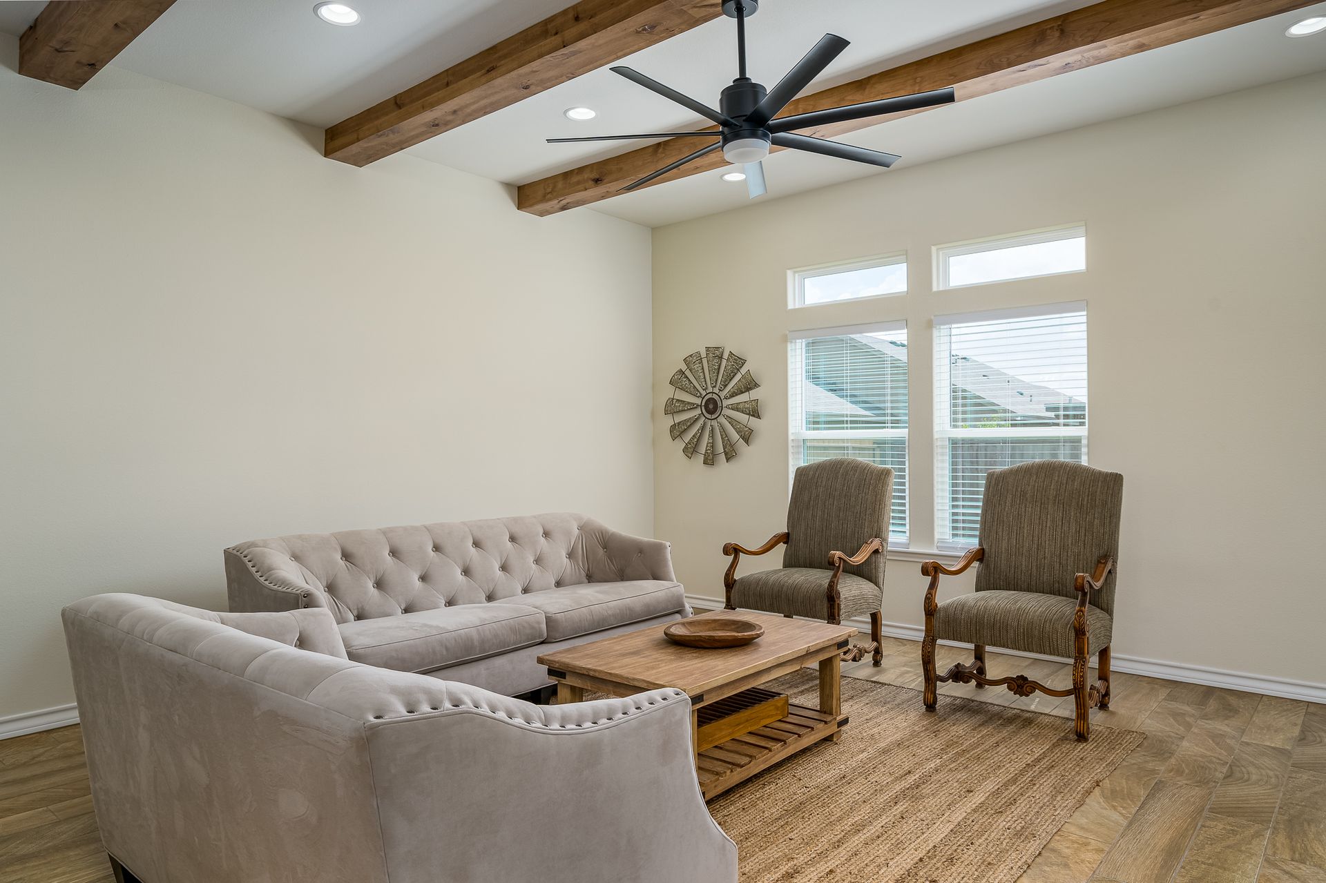 A living room with a couch , chairs , coffee table and ceiling fan.