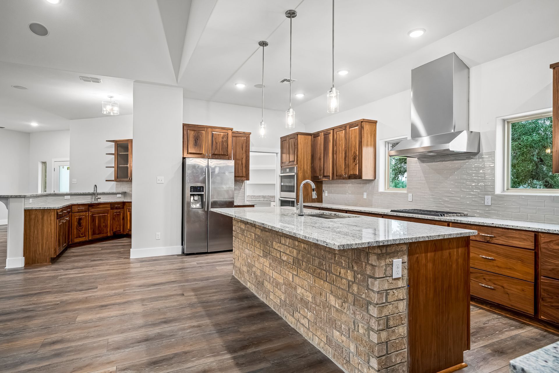 A kitchen with stainless steel appliances , granite counter tops , wooden cabinets and a large island.