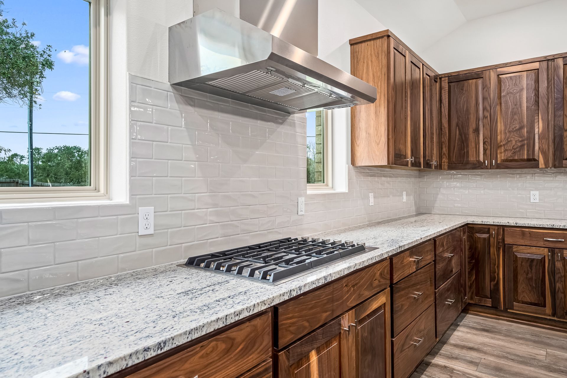 A kitchen with a stove top oven , granite counter tops , and wooden cabinets.