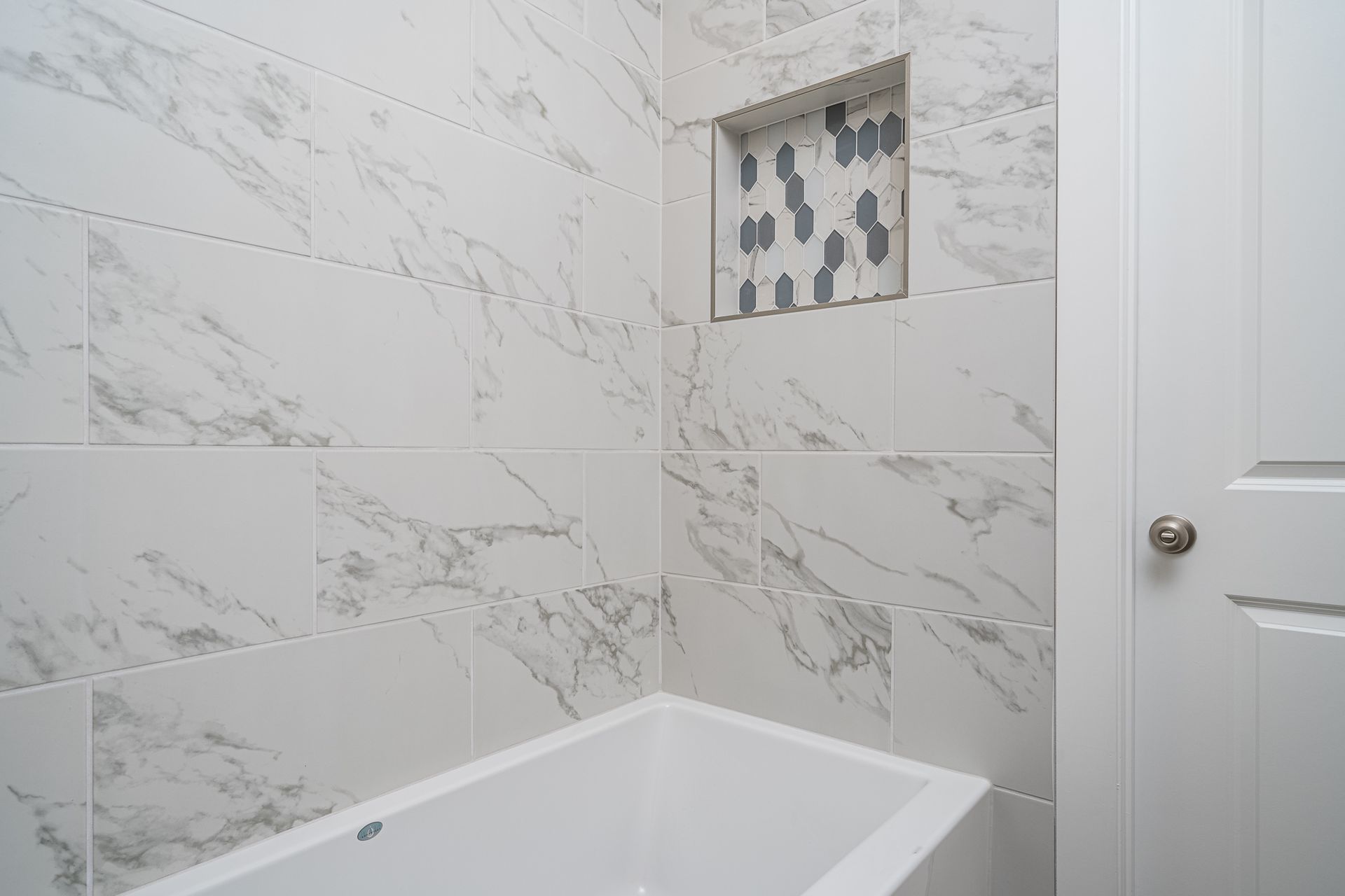 A bathroom with marble tiles and a bathtub.