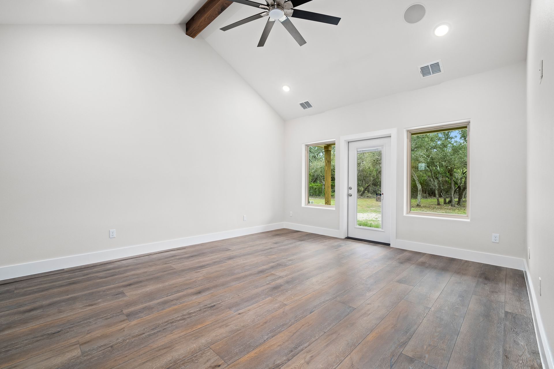 An empty living room with hardwood floors and a ceiling fan.