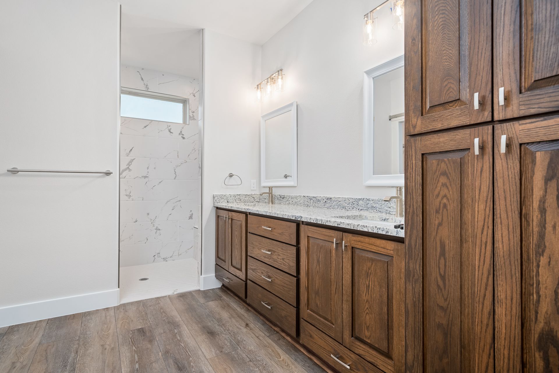 A bathroom with two sinks and a walk in shower.
