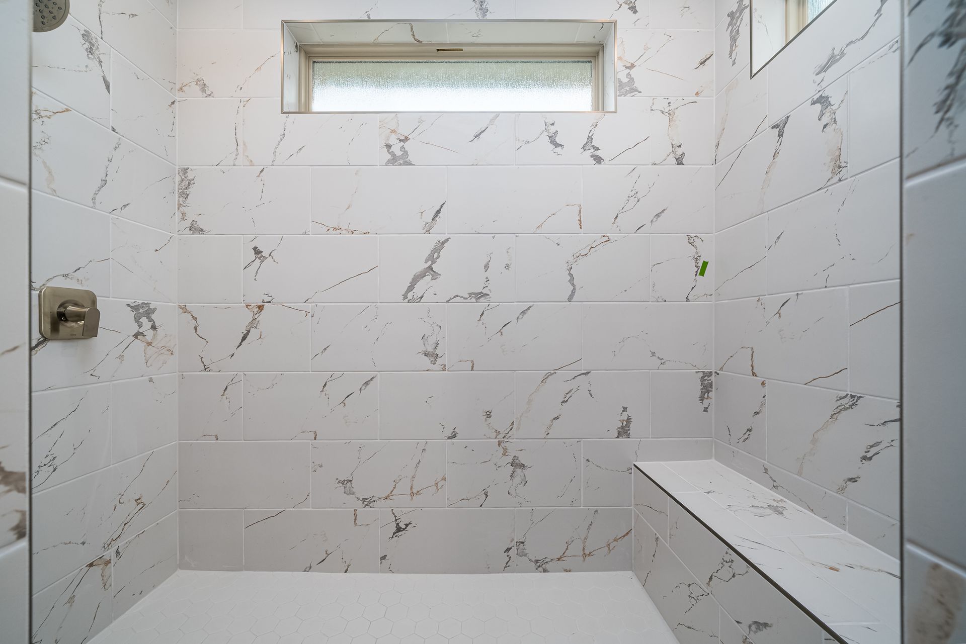 A bathroom with white tiles and a window.
