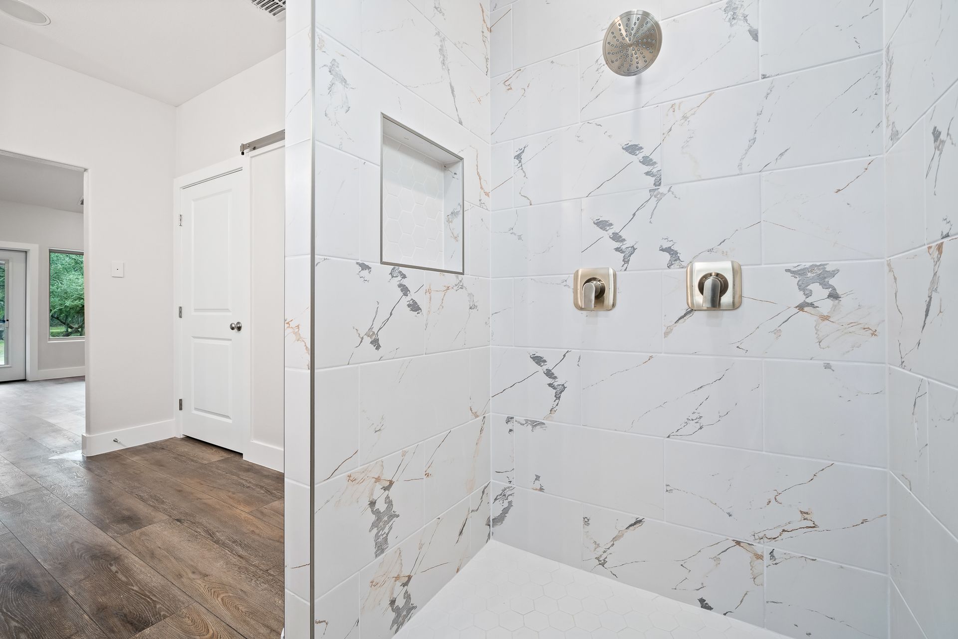 A bathroom with a walk in shower and a wooden floor.