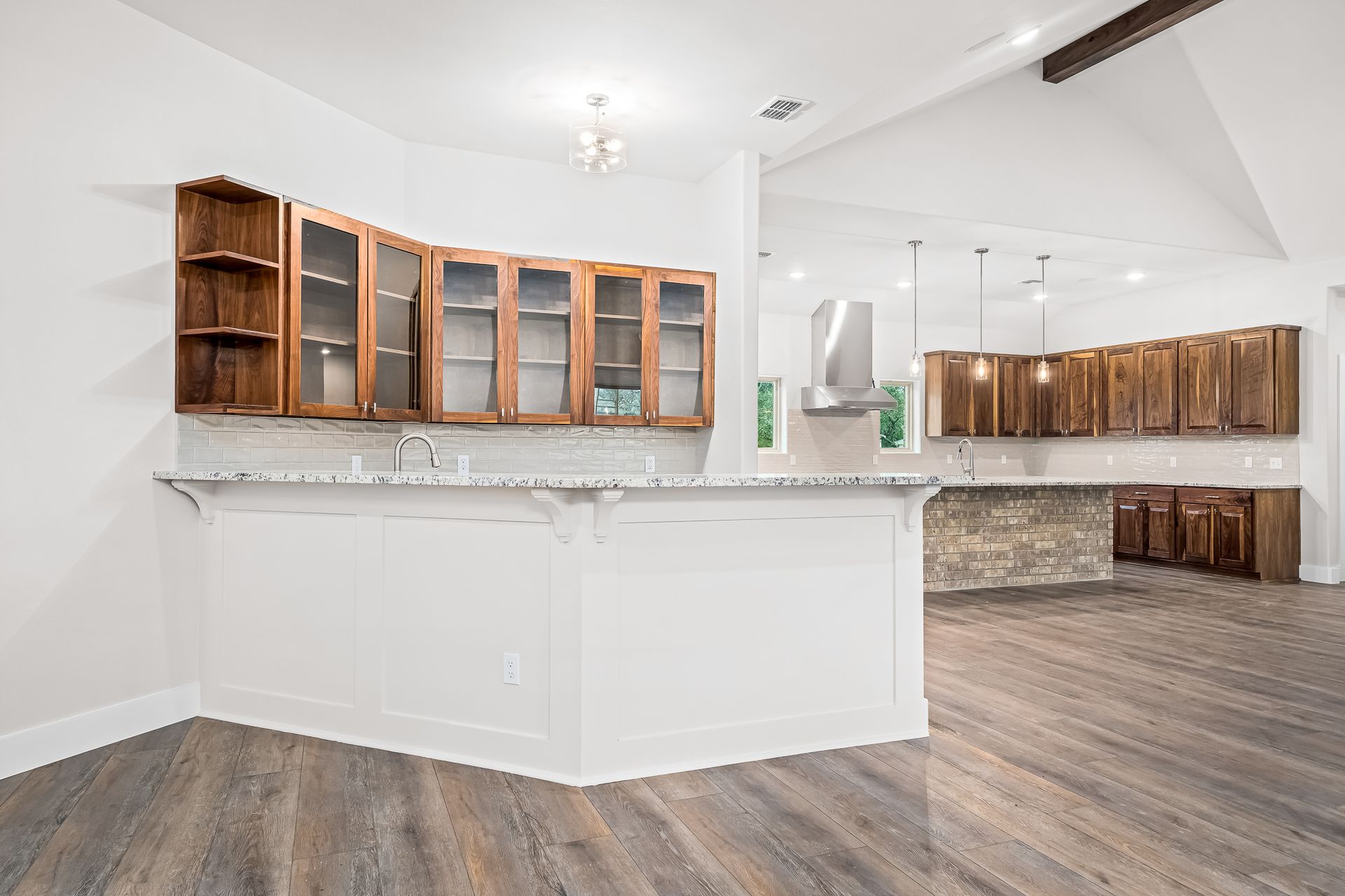 An empty kitchen with white cabinets and wooden floors.