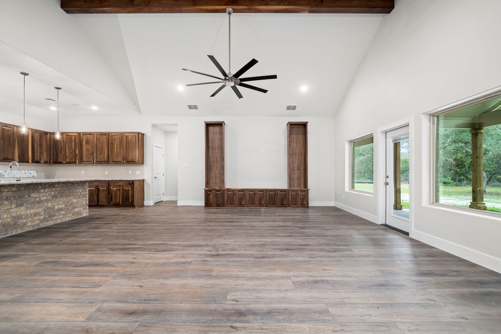 A large empty room with hardwood floors and a ceiling fan.