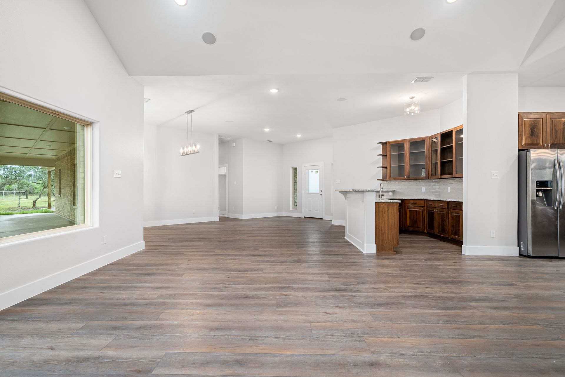 A large empty room with hardwood floors and a kitchen.