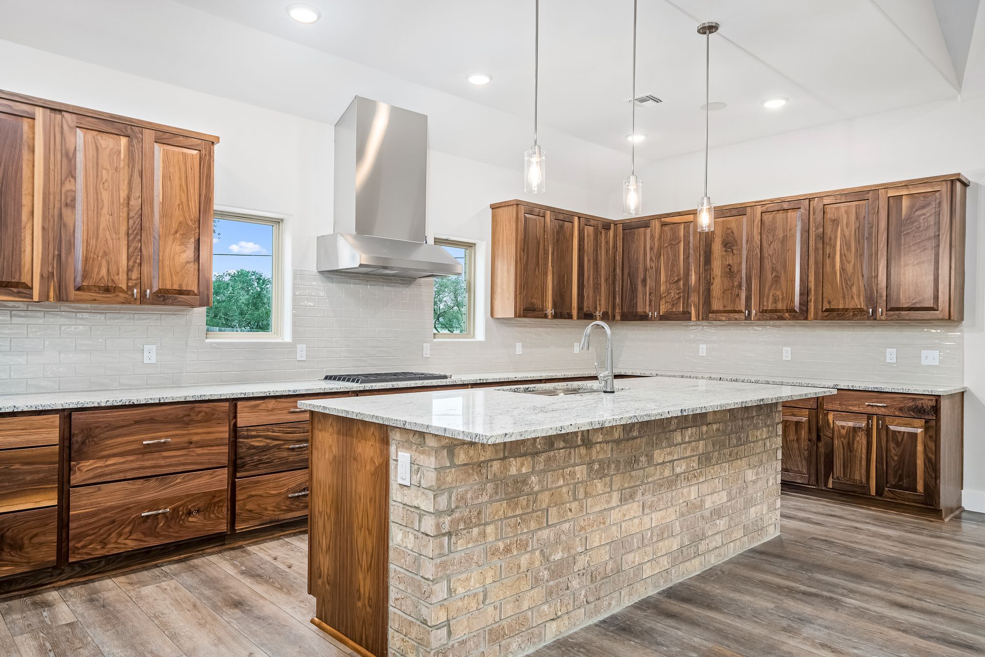 A kitchen with wooden cabinets , granite counter tops , and a large island.