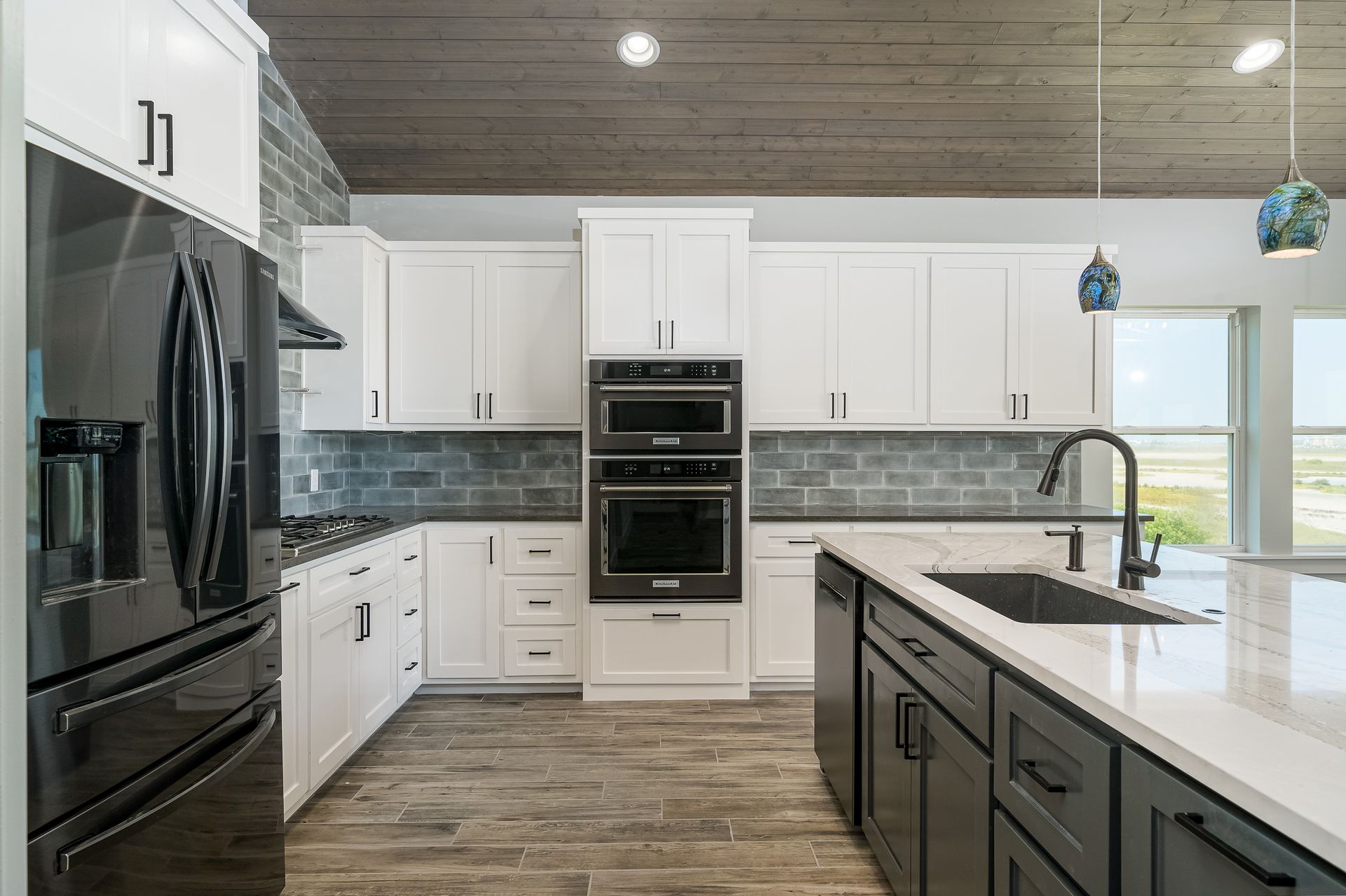 A kitchen with white cabinets , black appliances , and a large island.