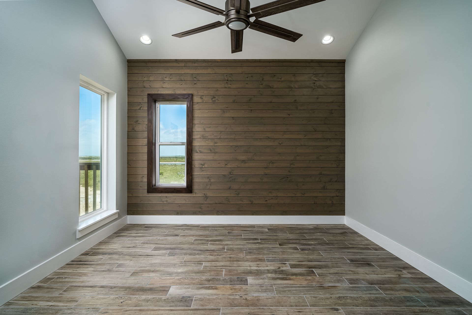 An empty room with a wooden wall and a ceiling fan.