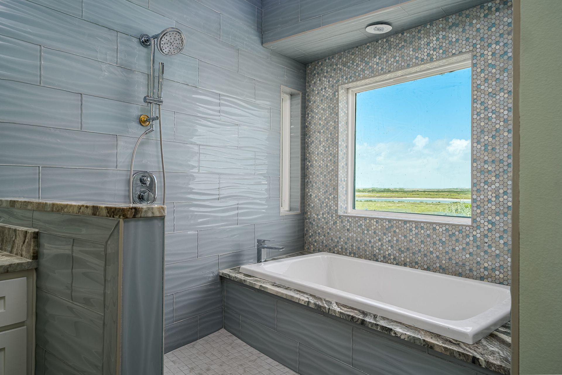 A bathroom with a tub , shower , sink and window.