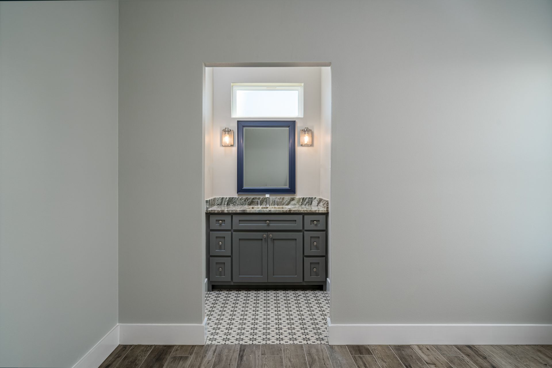 There is a bathroom with a sink and a mirror in the middle of the room.