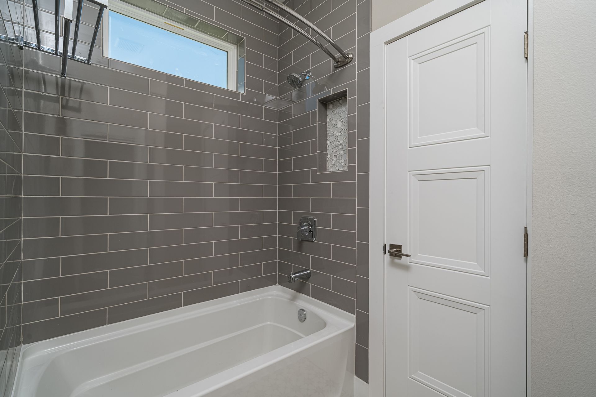 A bathroom with a bathtub , shower , and window.
