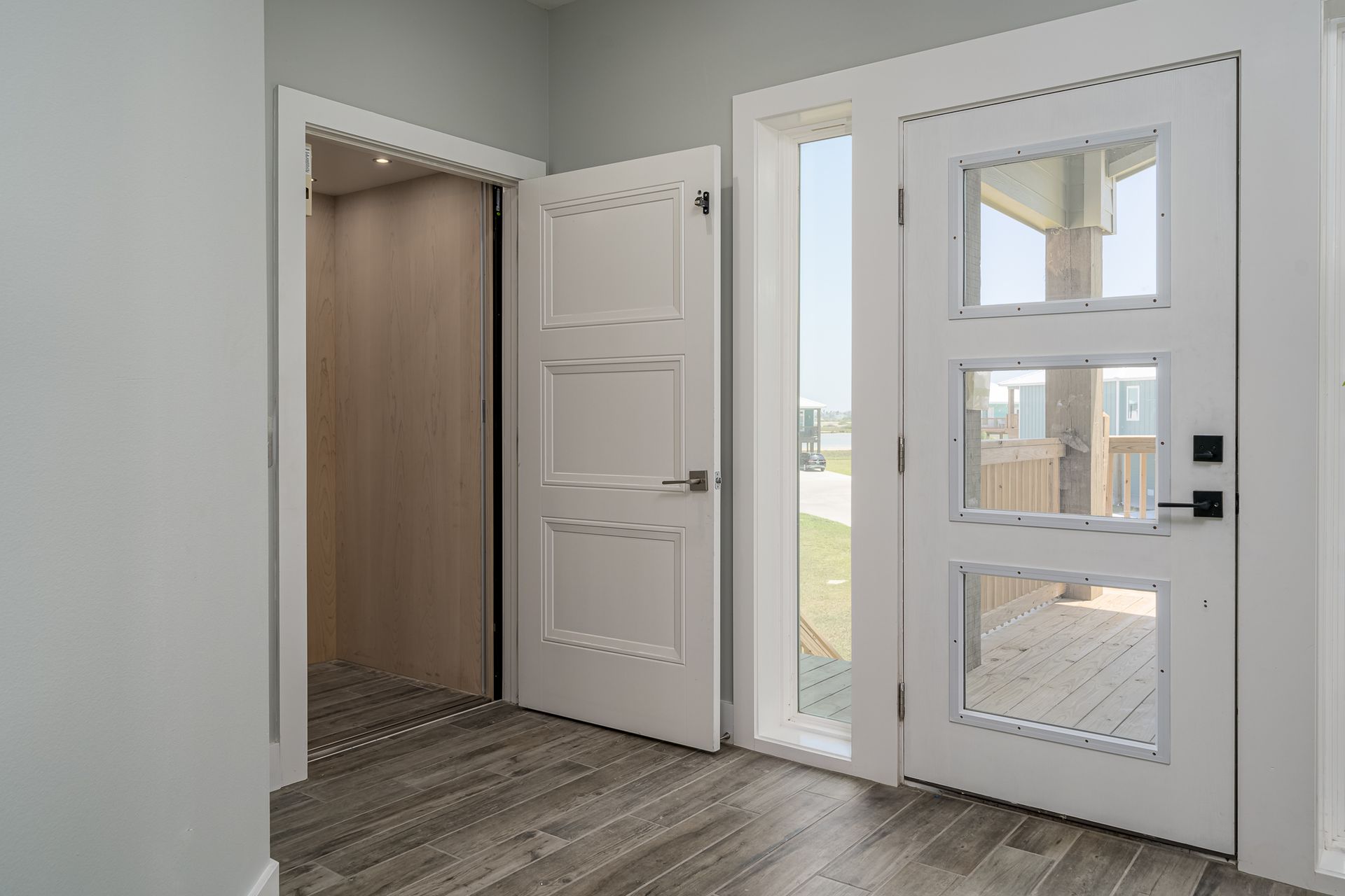 A hallway with a white door and a elevator in the background.