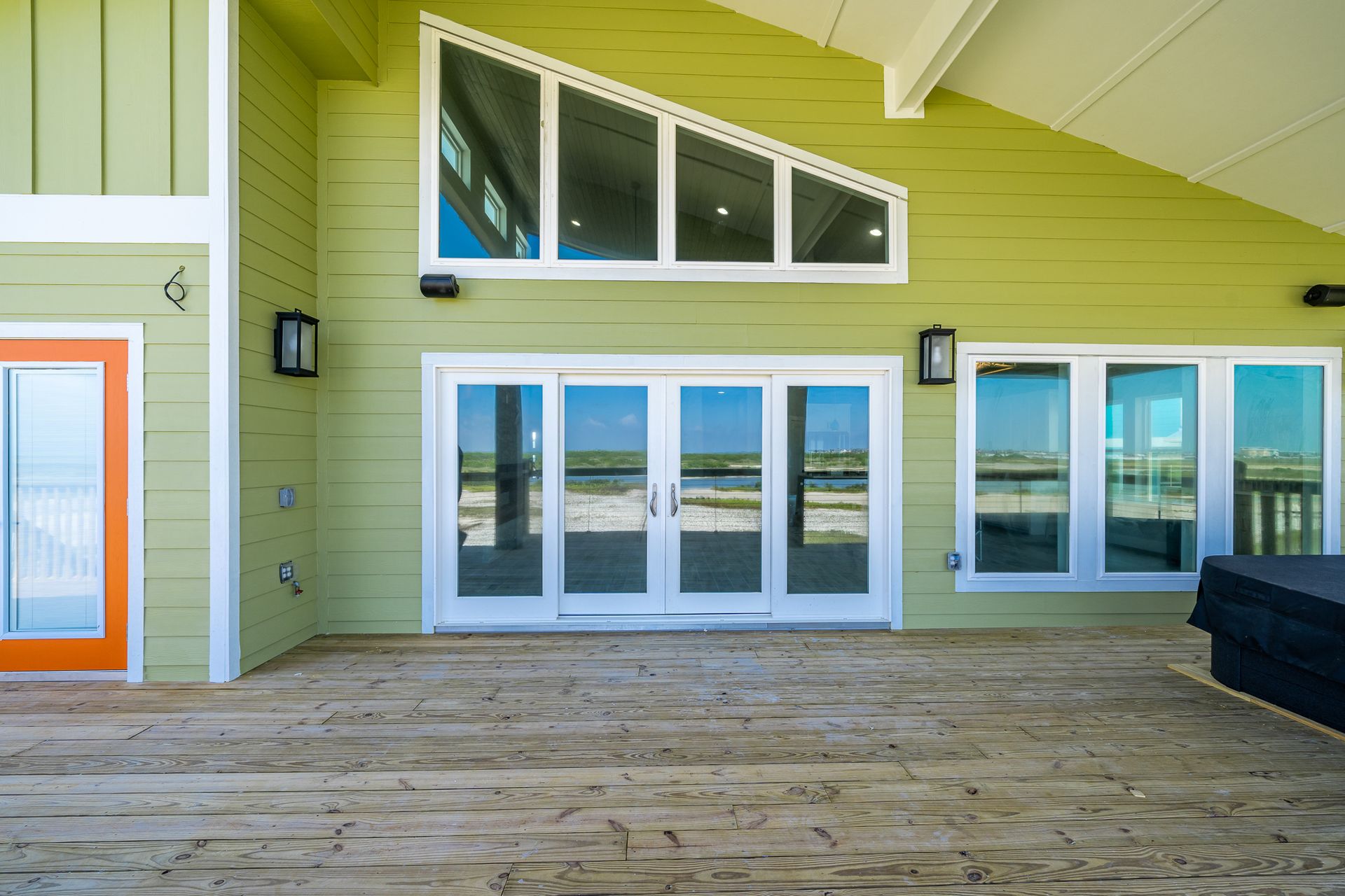 A green house with a large deck and lots of windows