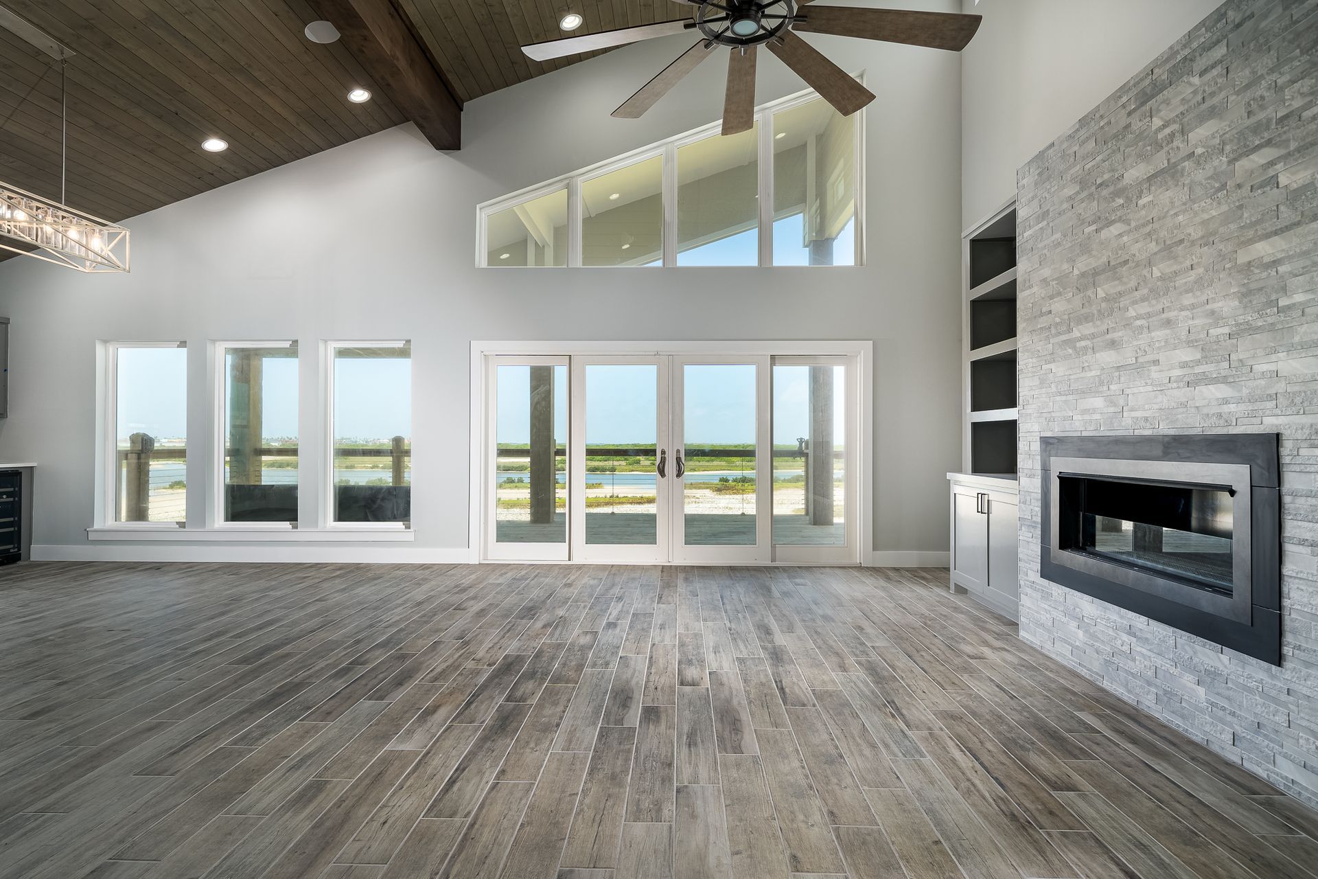 An empty living room with a fireplace and a ceiling fan.