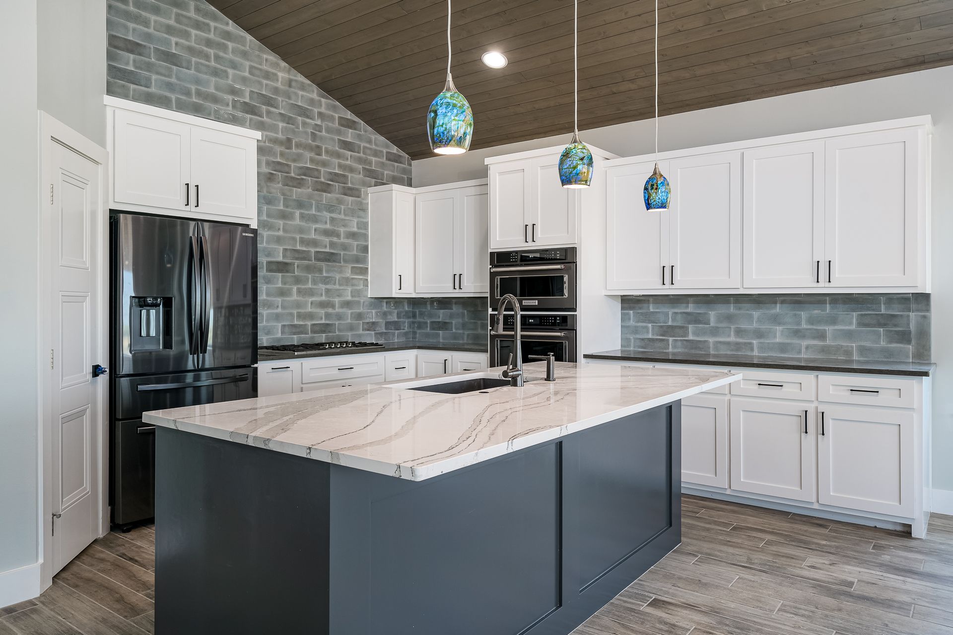 A kitchen with white cabinets , black appliances , and a large island.