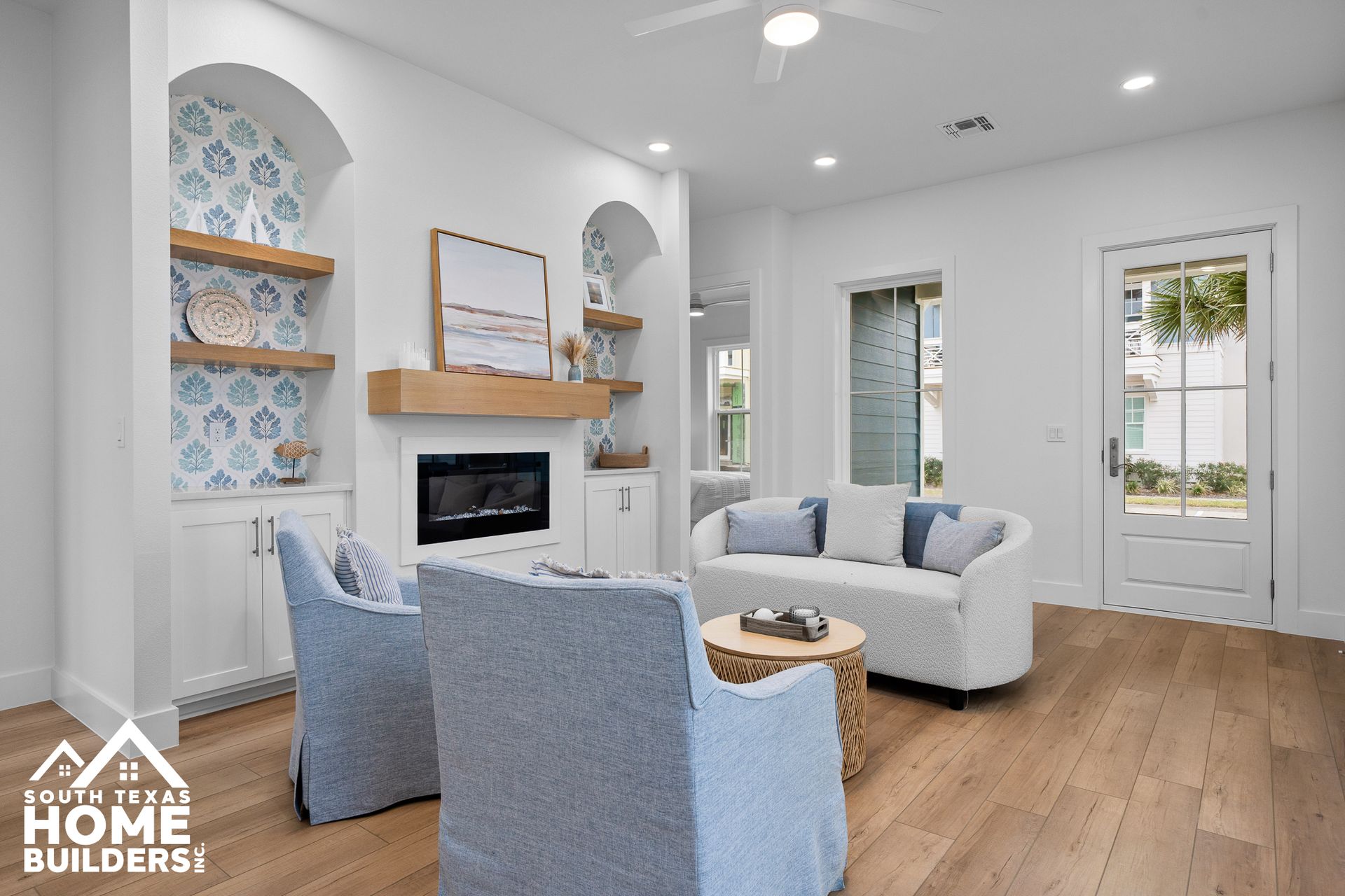 Living room with white walls, fireplace, blue chairs, and a white sofa.