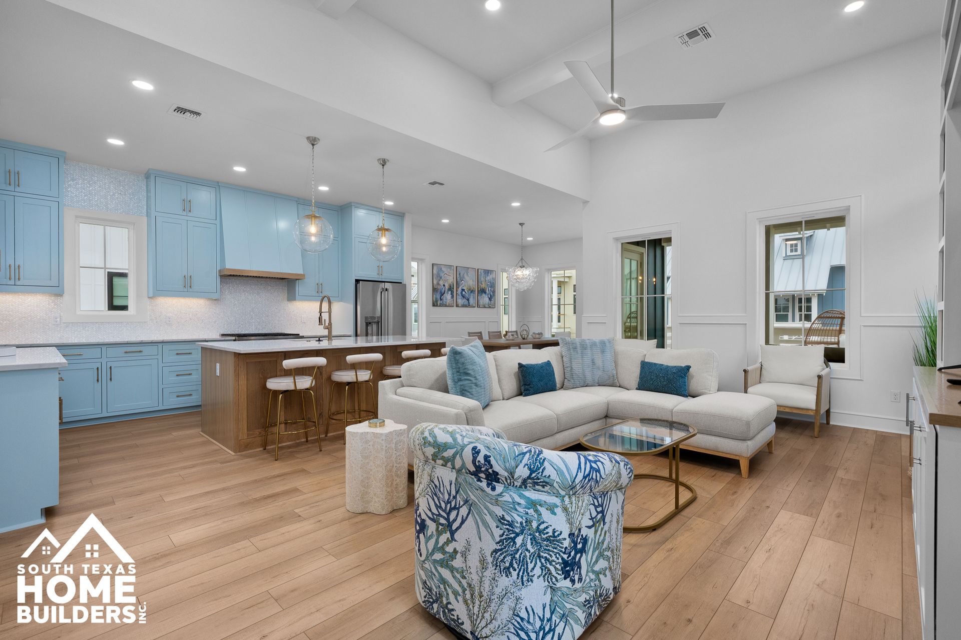 Open-concept living space with blue kitchen cabinets, light wood floors, and white walls.