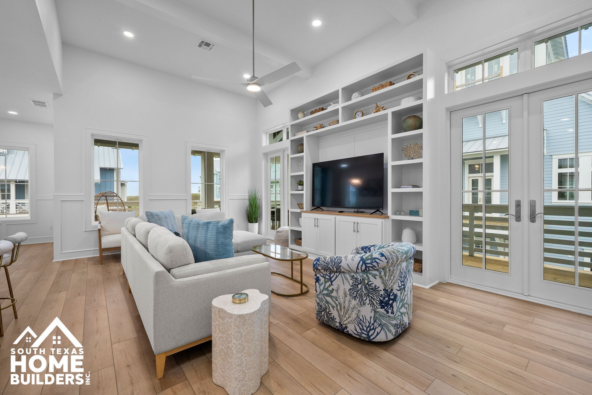 Living room with built-in shelves, sofa, blue armchair, and glass doors opening to a balcony.